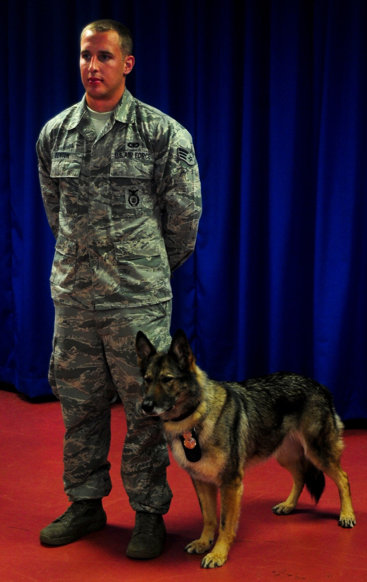 Senior Airman Brandon Denton, 6th Security Forces Squadron military working dog handler, stands with his now retired military working dog, Conny, during a retirement ceremony in honor of three military working dogs at MacDill Air Force Base, Fla., July 12, 2012. Denton and Conny have been partners for two years and upon her retirement was adopted by Denton. (U.S. Air Force photo by Senior Airman Melissa Paradise/Released/cropped to point of interest)
