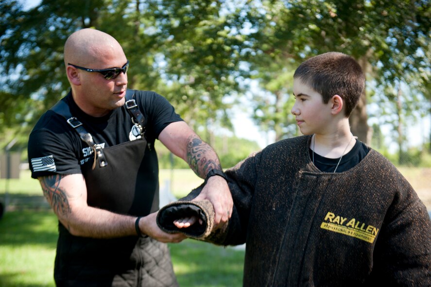 U.S. Air Force Tech. Sgt. David Smith, 23d Security Forces Squadron military working dog trainer, gives bite suit instructions to Christopher Carswell at Moody Air Force Base, Ga., July 10, 2012. Moody’s canine unit named Christopher an honorary dog handler for a day as he shadowed the unit and witnessed the various ways they protect the base. (U.S. Air Force photo by Staff Sgt. Jamal D. Sutter/Released)