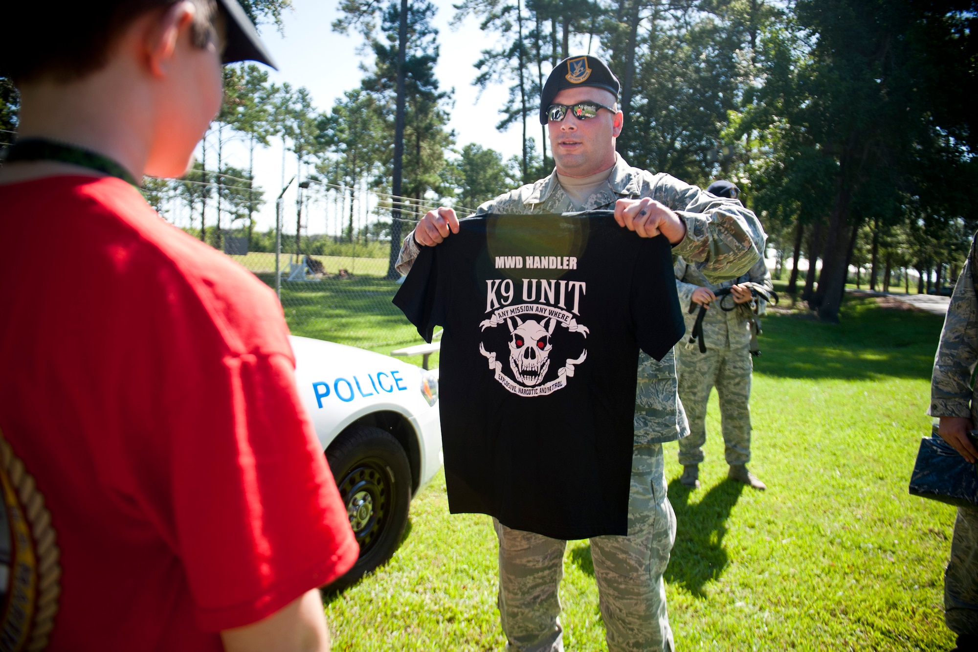 U.S. Air Force Tech. Sgt. David Smith, 23d Security Forces Squadron military working dog trainer, presents a MWD t-shirt to Christopher Carswell at Moody Air Force Base, Ga., July 10, 2012. Christopher shadowed the MWD unit for a day and witnessed what military canines do for Moody. (U.S. Air Force photo by Staff Sgt. Jamal D. Sutter/Released) 