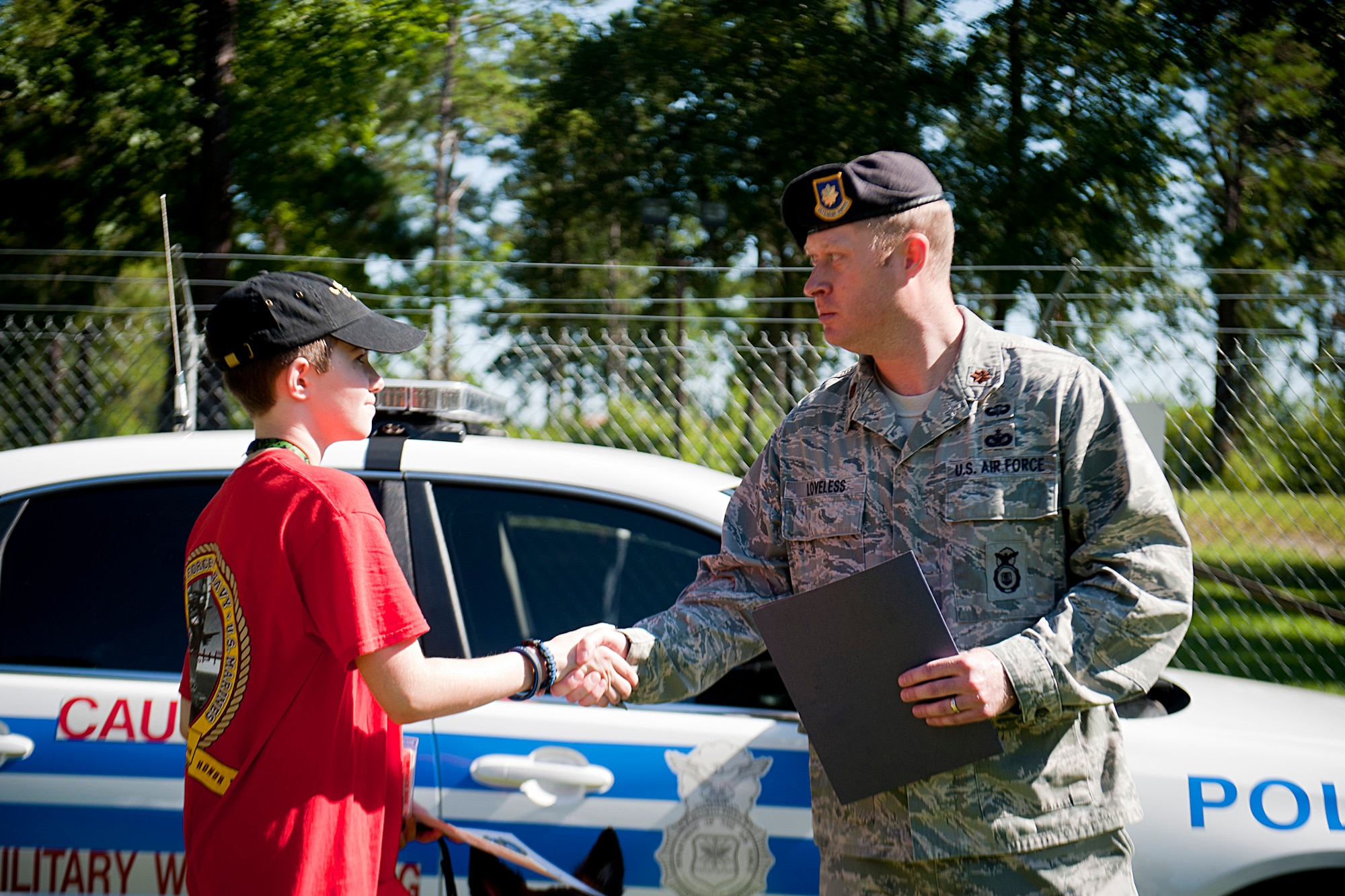U.S. Air Force Maj. Brian Loveless, 23d Security Forces Squadron commander, shakes hands with Christopher Carswell after presenting him with a certificate of appreciation at Moody Air Force Base, Ga., July 10, 2012. Loveless thanked Christopher for his charity work with an organization that helps provide service dogs to people who face various day-to-day challenges due to conditions like blindness and cancer. (U.S. Air Force photo by Staff Sgt. Jamal D. Sutter/Released) 
