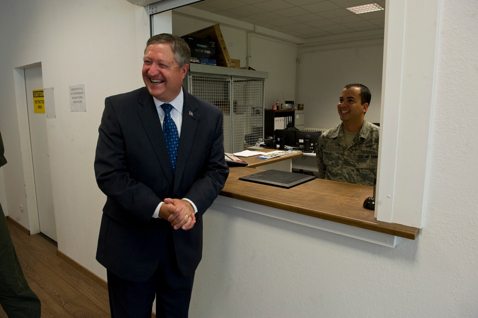Secretary of the Air Force Michael Donley shares a laugh with Staff Sgt. Jose Aviles, Heavy Airlift Wing postmaster, at Pápa Air Base, Hungary, July 11, 2012. The secretary visited the HAW to speak with Airmen about the direction of the Air Force, meet with them on the job and pay personal attention to the service members. (U.S. Air Force photo/Master Sgt. Wayne Clark)