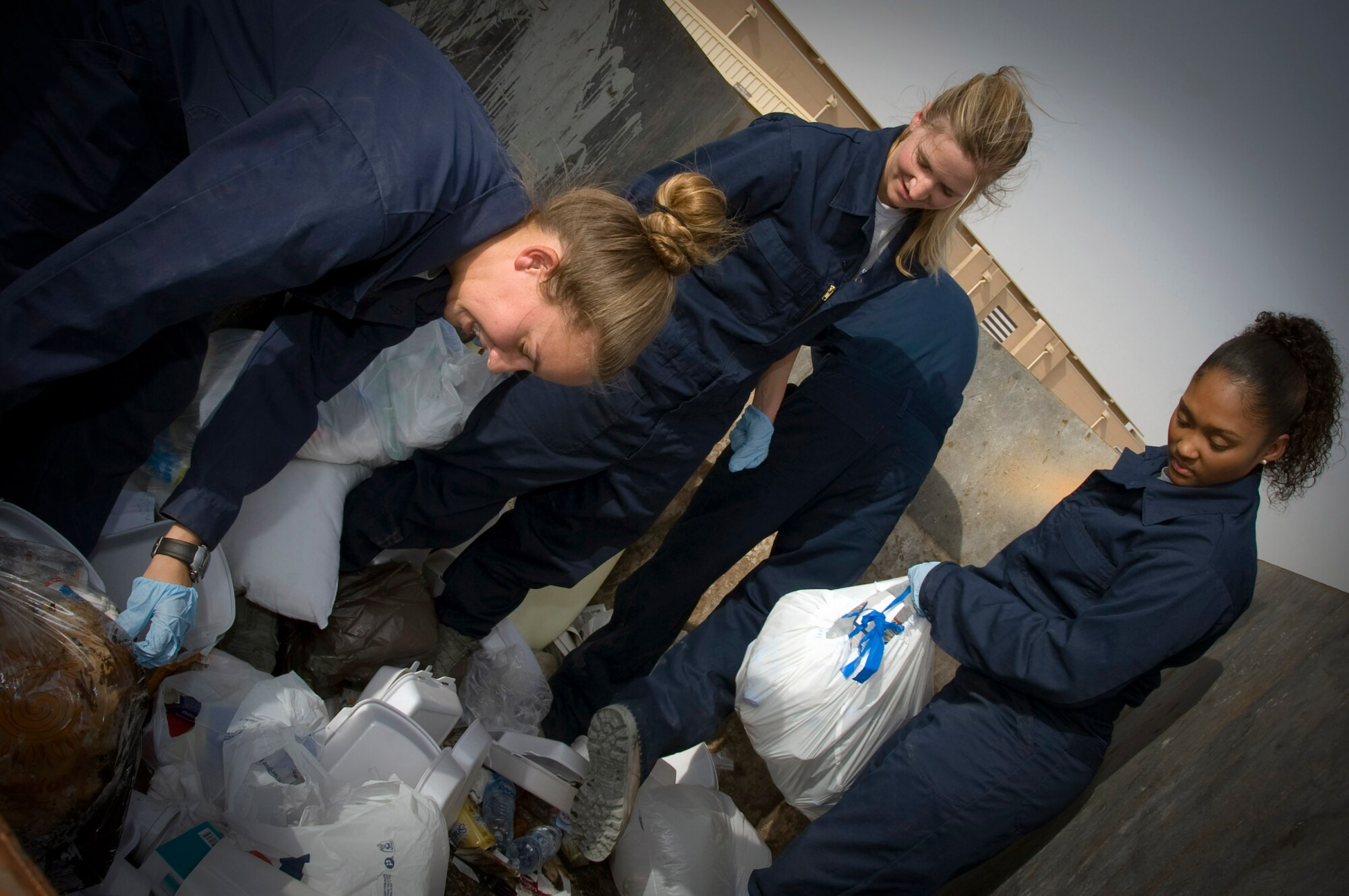 Members from the Escort Flight - Tango Element also known as ?Dumpster Divers? sort through trash looking for operation security violations in Southwest Asia, July 2, 2012. Last month alone, Tango Element recovered more than 1,900 OPSEC violations. Airmen from Tango Element are assigned to the 379th Expeditionary Civil Engineer Squadron. (U.S. Air Force photo/Staff Sgt. Sheila deVera)