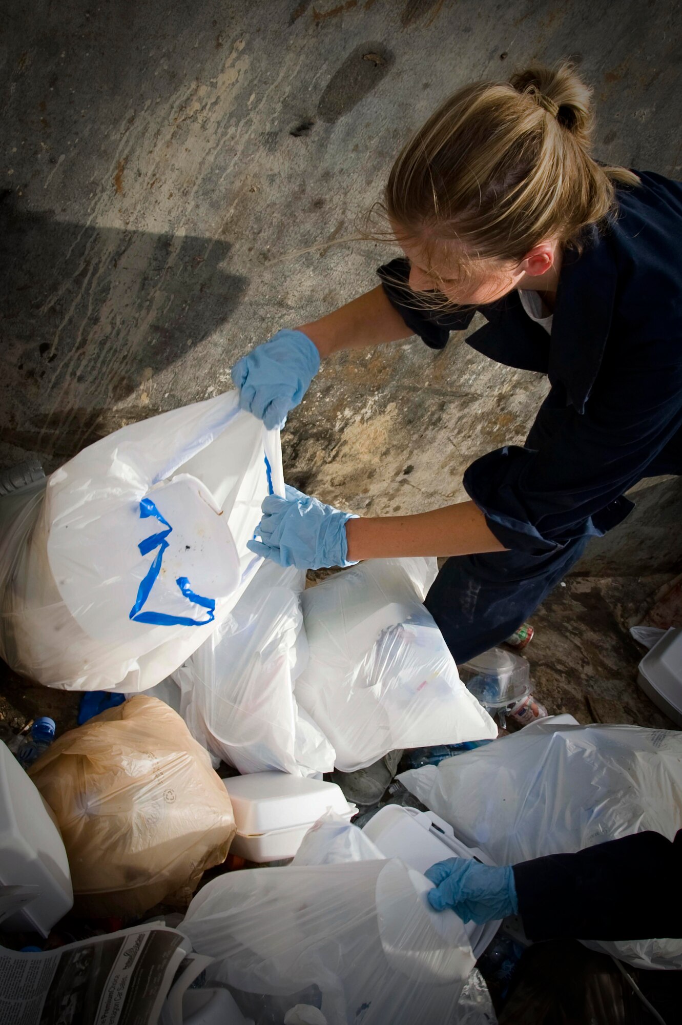 Members from the Escort Flight - Tango Element also known as ?Dumpster Divers? sort through trash looking for operation security violations in Southwest Asia, July 2, 2012. Last month alone, Tango Element recovered more than 1,900 OPSEC violations. Airmen from Tango Element are assigned to the 379th Expeditionary Civil Engineer Squadron. (U.S. Air Force photo/Staff Sgt. Sheila deVera)