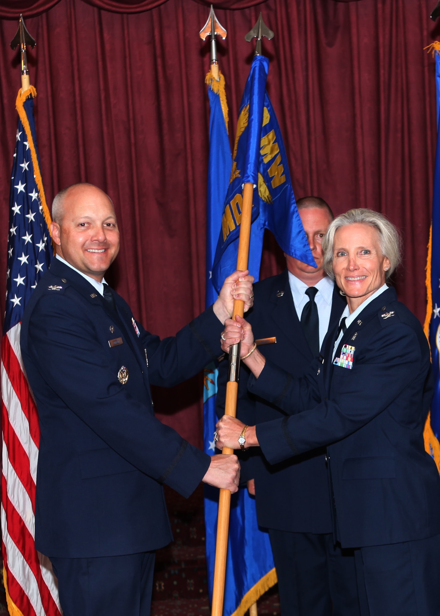 Col. Christopher Coffelt, 90th Missile Wing commander, presents Col. Bridget Gregory, 90th Medical Group commander, with the 90th MDG guidon during the 90th MDG change-of-command ceremony at the Trail's End Club July 10. (U.S. Air Force photo by Matt Bilden)