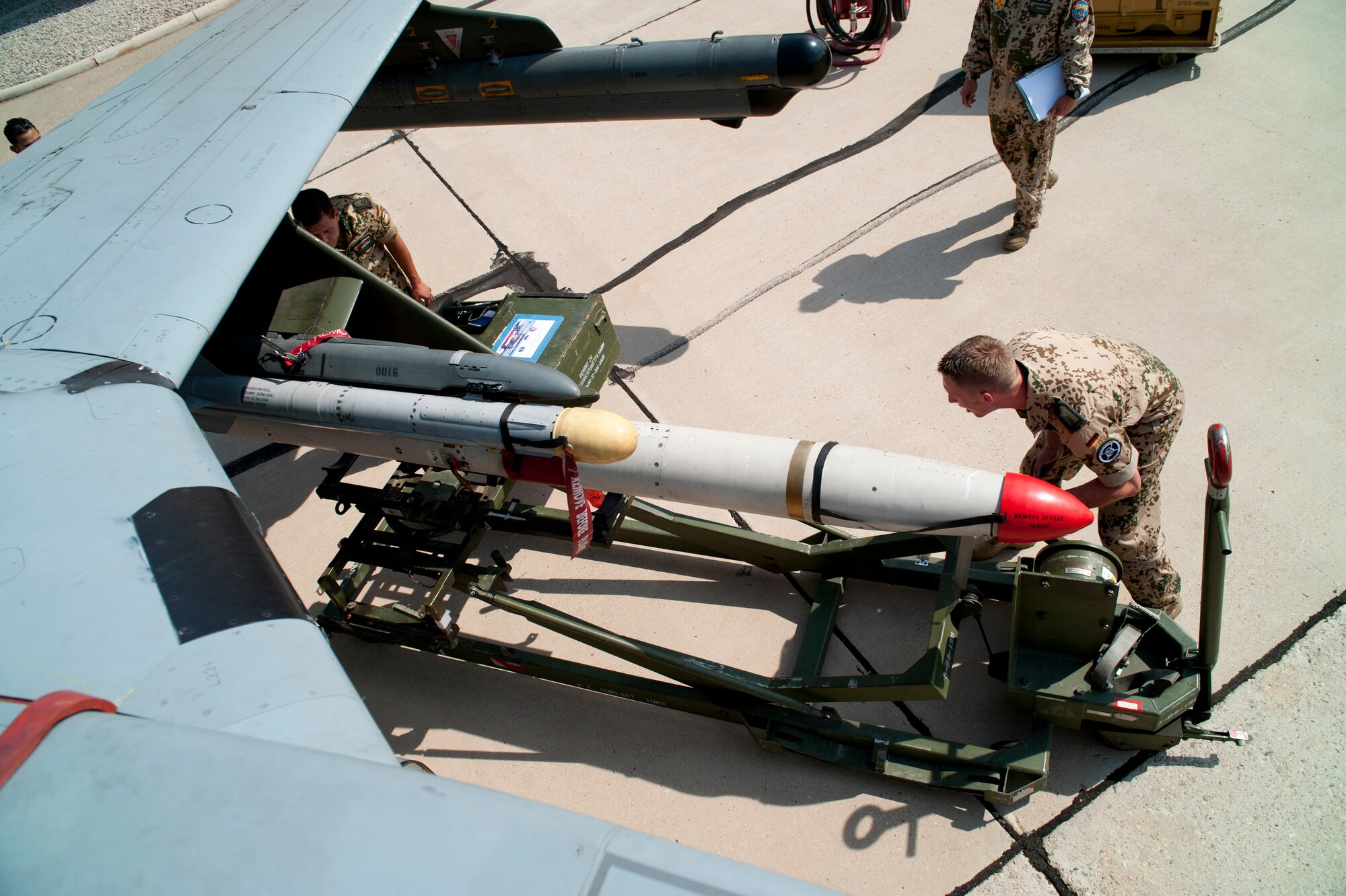 German Air Force Tech. Sgts. Carsten Wedemeyer and Martin Wattler, German Air Force Flying Training Center crew chiefs, prepares an AIM-9 Sidewinder to be loaded onto a Tornado during a quarterly load-crew competition at Holloman Air Force Base, N.M., July 13. The GAF load-crew competed in the load-crew competition to have their skills evaluated alongside the U.S. Air Force F-22 Raptor and MQ-9 Reaper load crews. For the competition, points are awarded during the weapons loading, tool kit inspection, and uniform inspection. (U.S. Air Force photo by Airman First Class Daniel Liddicoet/Released)