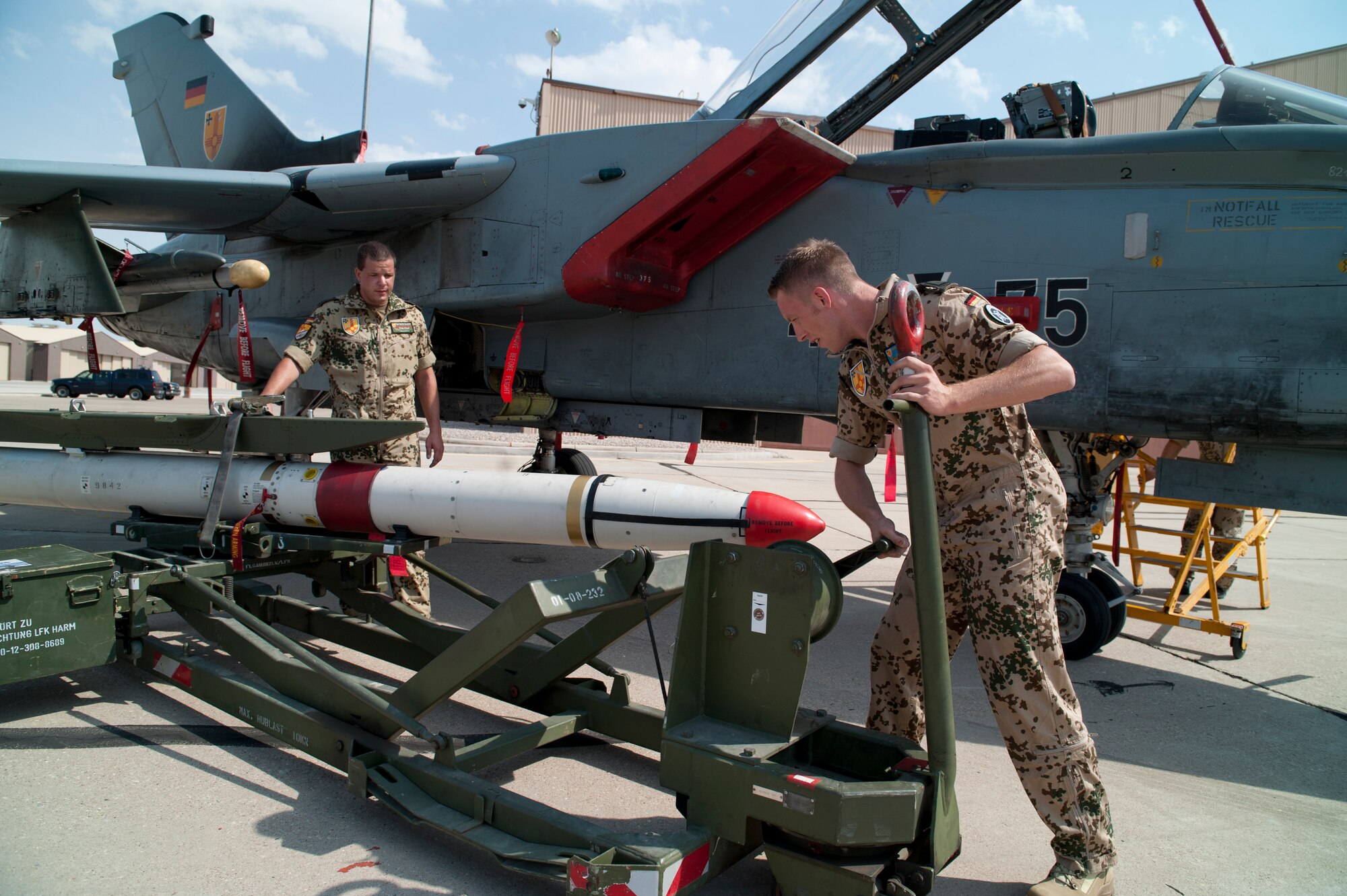 German Air Force Tech. Sgts. Carsten Wedemeyer and Martin Wattler, both crew chiefs from the German Air Force Flying Training Center, prepare a Tornado to be loaded with an AIM-9 Sidewinder during a quarterly load-crew competition at Holloman Air Force Base, N.M., July 13. The GAF load-crew competed in the load-crew competition to have their skills evaluated alongside the U.S. Air Force F-22 Raptor and MQ-9 Reaper load crews. For the competition, points are awarded during the weapons loading, tool kit inspection, and uniform inspection. (U.S. Air Force photo by Airman First Class Daniel Liddicoet/Released)