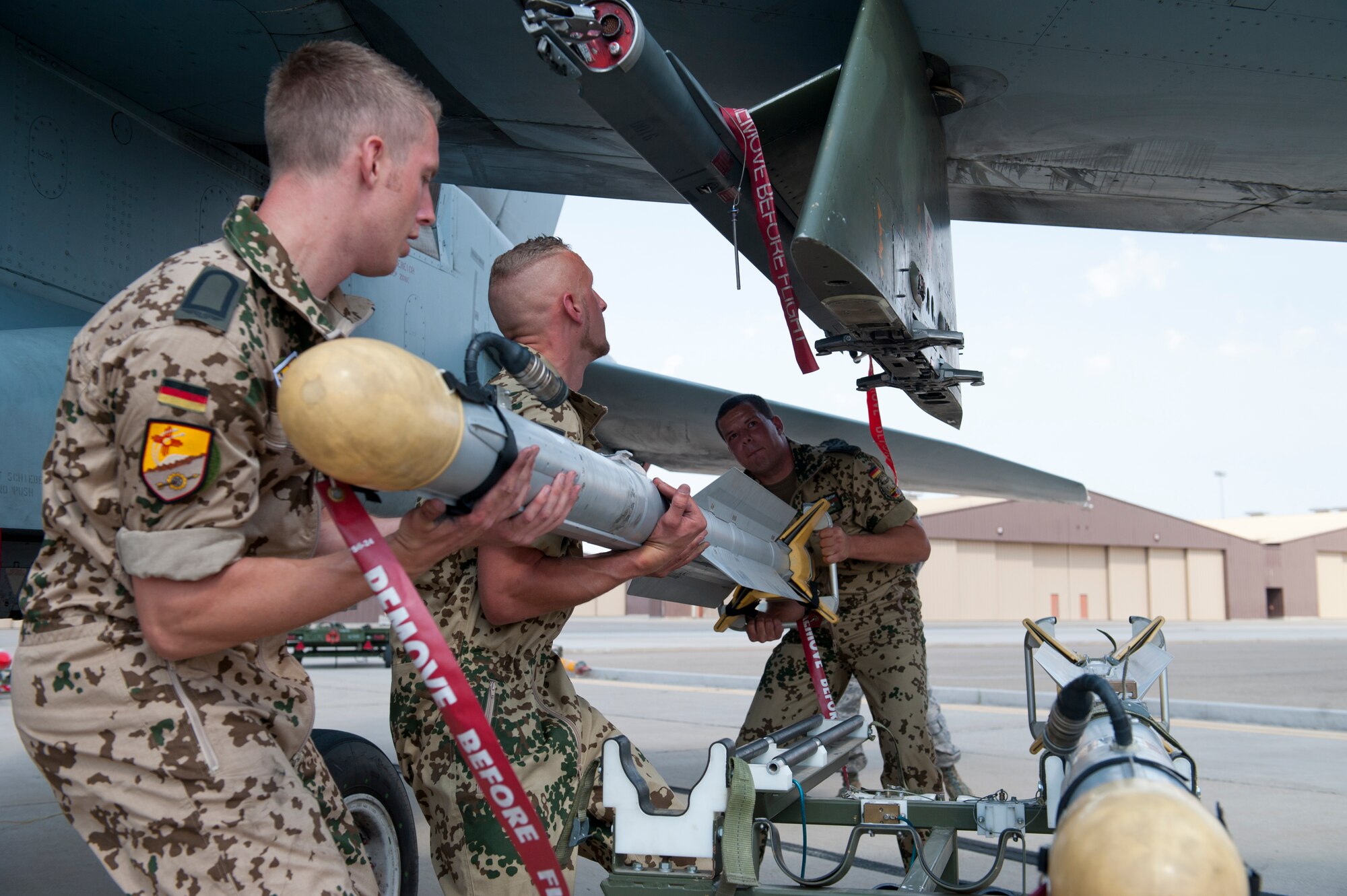 German Air Force Staff Sgt. Carsten Wedemeyer and German Air Force Tech Sgts. Jens Feddersen and Martin Wattler, all crew chiefs from the German Air Force Flying Training Center, load a GBU-24 laser-guided bomb onto a Tornado during a quarterly load-crew competition at Holloman Air Force Base, N.M., July 13. The crew loaded a GBU-32 bomb and an AIM-9 Sidewinder during the competition to display their warfighting skills, while avoiding safety and procedural errors. The GAF crew also competed against U.S. Air Force F-22 Raptor and MQ-9 Reaper load crews. (U.S. Air Force photo by Airman First Class Daniel Liddicoet/Released)