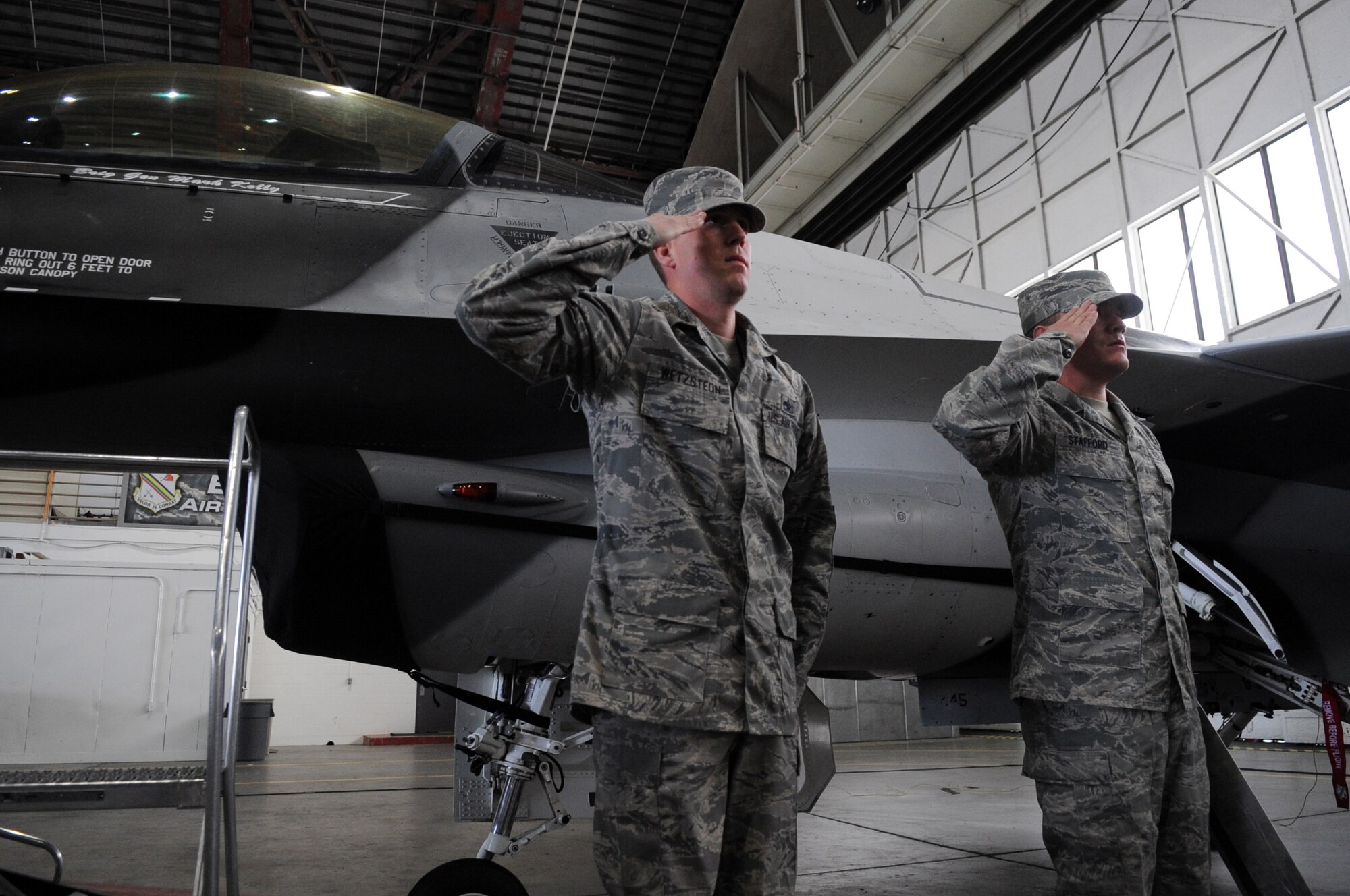 U.S. Air Force Tech. Sgt. Andrew Wetzsteon and Airman 1st Class Daniel Stafford, 354th Aircraft Maintenance Squadron crew chiefs, salute Brig. Gen. Mark Kelly, incoming 354th Fighter Wing commander, during a change of command ceremony July 13, 2012, Eielson Air Force Base, Alaska. Kelly assumed command from Brig. Gen. James Post III. (U.S. Air Force photo/Airman 1st Class Lauren-Taylor Garcia)