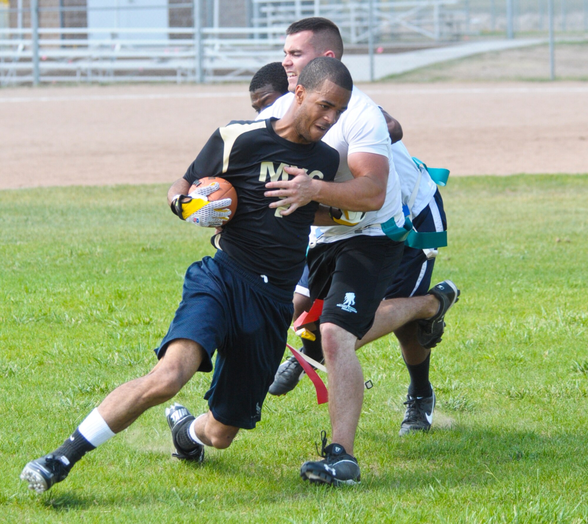 Airman 1st Class Greg Jones, 90th Maintenance Group missile handling team, attempts to run around defenders but has his flag snatched a member of the team playing for the 90th Logistics Readiness Squadron during a flag football tournament hosted by the Under 21 Responsible and Resilient Program July 5 on the F. E. Warren ball fields. (U.S. Air Force photo by Airman 1st Class Jason Wiese)