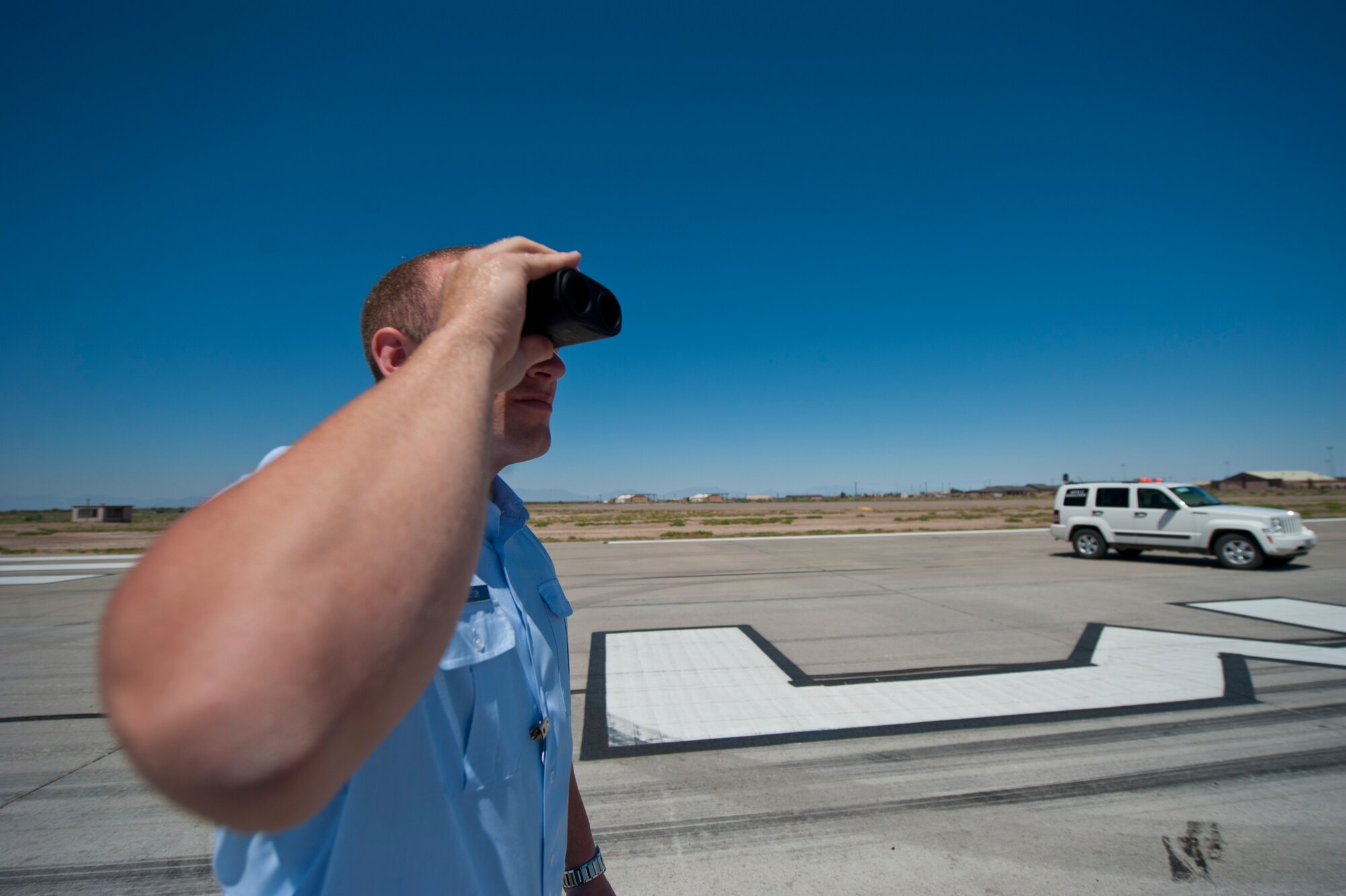 Senior Airman Christopher Proctor, 49th Operations Support Squadron airfield manager, uses a range finder to estimate the distance of objects on the airfield at Holloman Air Force Base, N.M., June 25. Airfield managers must know the exact whereabouts of all incoming and outgoing aircraft on the airfield. (U.S. Air Force photo by Airman 1st Class Daniel E. Liddicoet/Released)