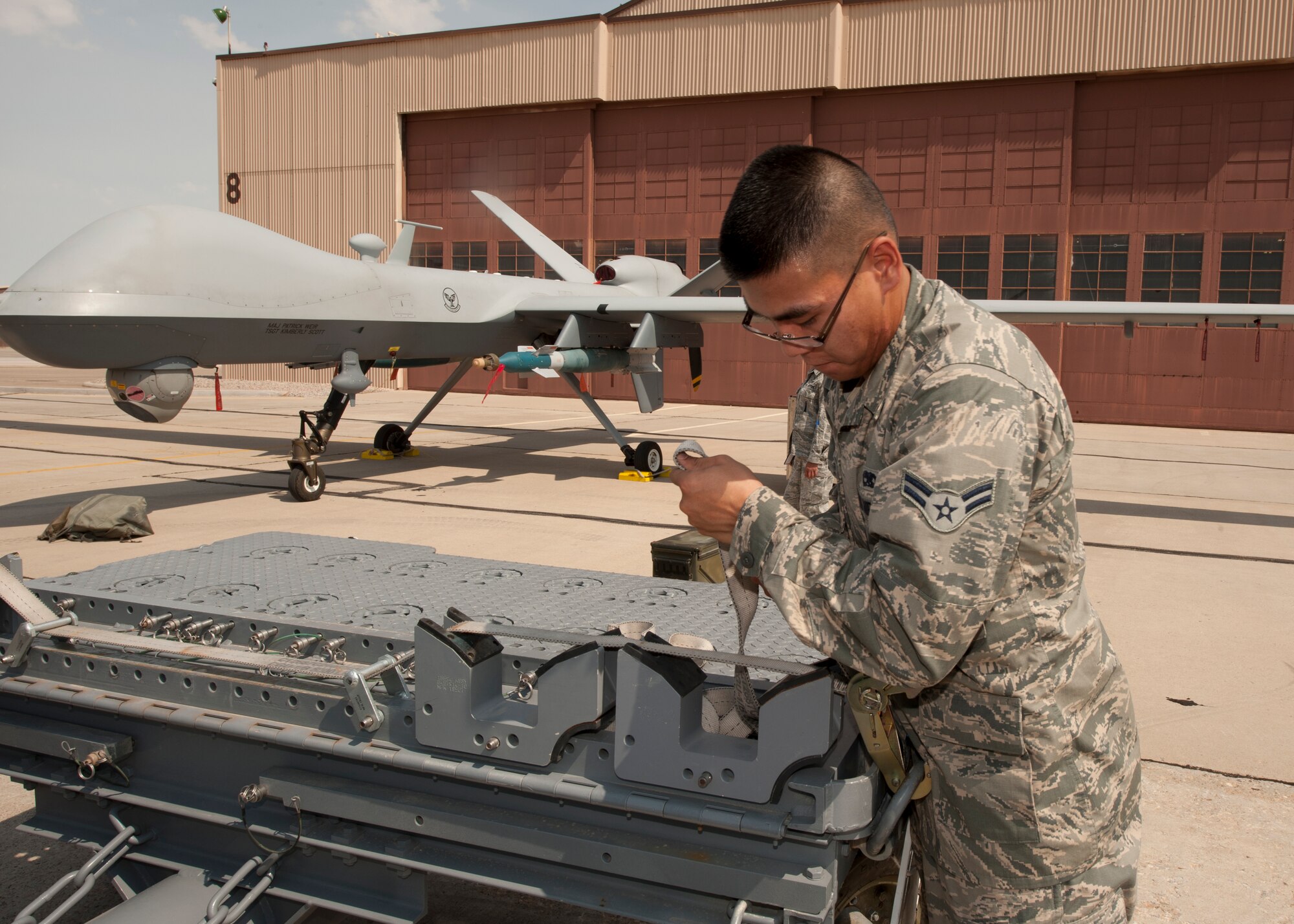 Airman 1st Class Binh [last name withheld due to operational security concerns], 49th Maintenance Group, tightens straps during a quarterly load-crew competition at Holloman Air Force Base N.M., July 13. For the competition, three load teams competed against each other to determine who can load weaponry onto their aircraft quickly, without safety or mechanical errors. Nguyen’s MQ-9 crew competed against crews from the F-22 Raptor and German Tornado platforms for the title of Holloman’s best weapons load crew. (U.S. Air Force photo by Airman Leah Ferrante/Released)