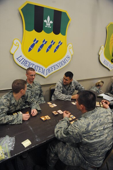 Airmen with temporary duty orders to Nellis Air Force Base, Nev., play cards to pass the time as they wait for their chartered flight at Hoban Hall on Barksdale Air Force Base, La., July 12. According to the defense transportation regulation, all DoD passengers on a chartered flight must arrive three hours prior to departure to allow personnel to be ready in the event the chartered aircraft arrives early. After processing through the deployment line, Airmen are not permitted to leave the waiting area unless authorized to do so. The Airmen left to participate in the Red Flag exercise which provides realistic combat scenarios for aircrews from the U.S., NATO and allied countries. (U.S. Air Force photo/Airman 1st Class Micaiah Anthony)(RELEASED)