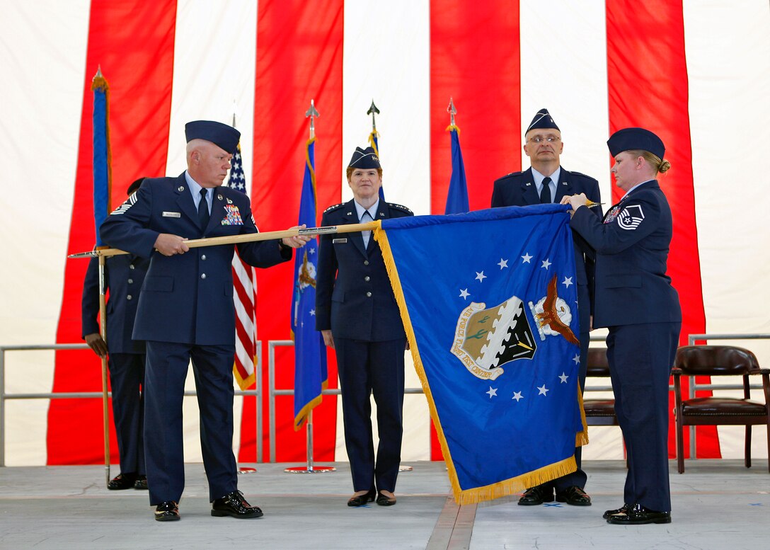 Chief Master Sgt. Christopher McCollor, Air Force Test Center command chief, ceremoniously rolls up the Air Force Flight Test Center flag, with the assistance of Master Sgt. Stephanie Brown, during a re-designation ceremony in Hangar 1600 July 13. Gen. Janet Wolfenbarger, commander of Air Force Materiel Command, and Brig. Gen. Arnold Bunch Jr., AFTC commander, presided over the ceremony. Under Bunch's
leadership, the center will have oversight of work carried out at three primary locations across AFMC, including Edwards, Eglin AFB, Fla., and Arnold AFB, Tenn. (U.S. Air Force photo/Jet Fabara)
