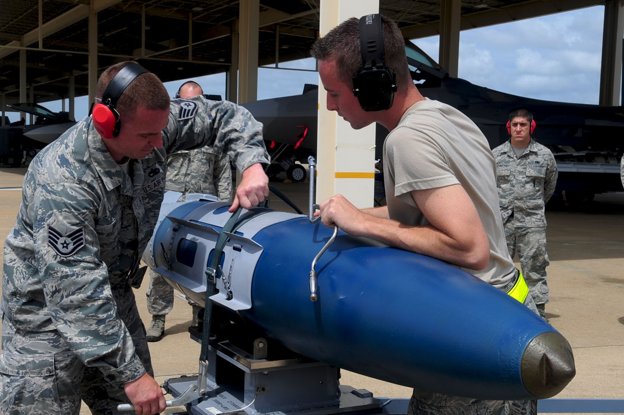U.S. Air Force Staff Sgt. Justin Hall, left, and Airman 1st Class Ryan Mabbit, both 27th Aircraft Maintenance Unit weapons loaders, restrain ordnance during a weapons loading competition at Langley Air Force Base, Va., July 12, 2012. The 27th and 94th AMUs hold quarterly competitions, evaluating the ability of Airmen to accurately and rapidly load weapons onto an aircraft. (U.S. Air Force photo by Staff Sgt. Ashley Hawkins/Released)