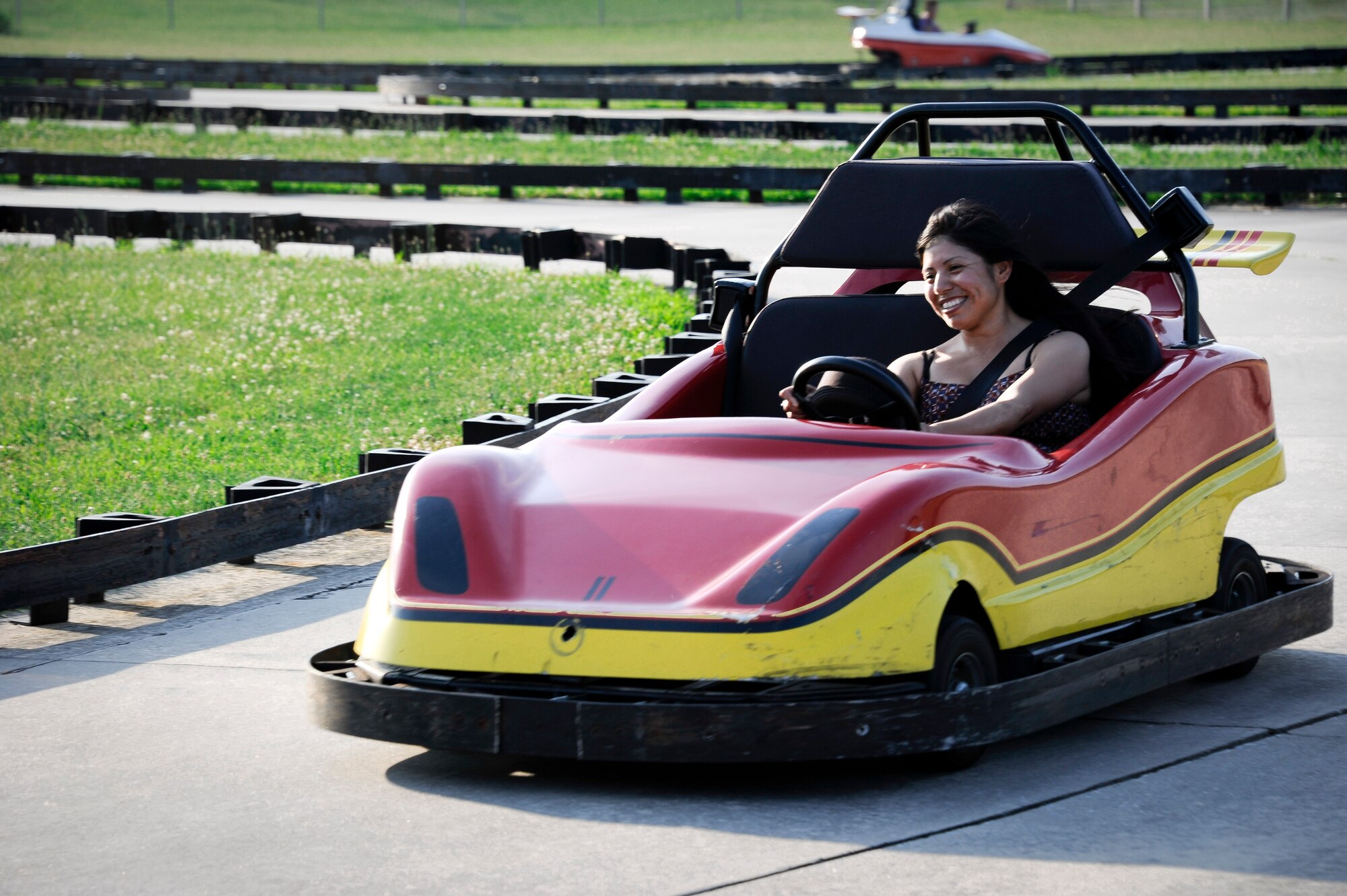 Army Staff Sgt. Cristina Salavar, 1040th Quartermaster company water purification specialist, races around the go-cart track during the annual Fourth of July celebration at Doughboy Field here. The go-cart track was one of several activities available during this year’s event. (U.S. Air Force photo by Airman 1st Class Ryan Throneberry/Released)