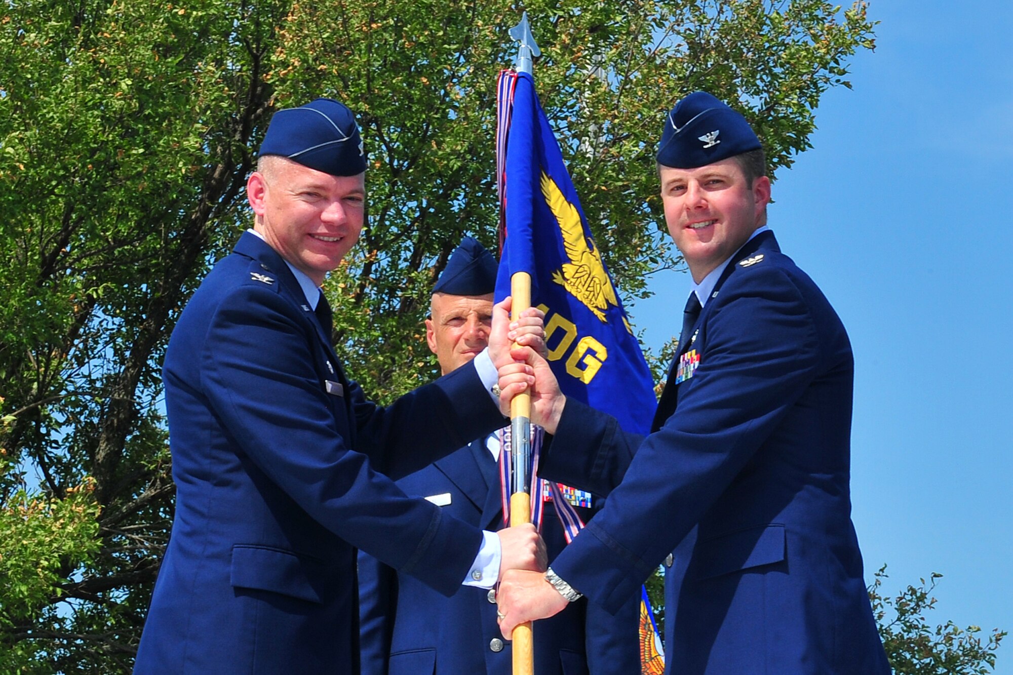 U.S. Air Force Col. John Rauch, 55th Wing commander, passes the 55th Medical Group guidon to incoming 55th MDG commander U.S. Air Force Col. Stephen Mounts, during the 55th MDG change of command ceremony held outside the Ehrling Bergquist Clinic on Offutt Air Force Base, Neb., July 12. Mounts is coming to Offutt from Joint Base Langley-Eustis, Va.