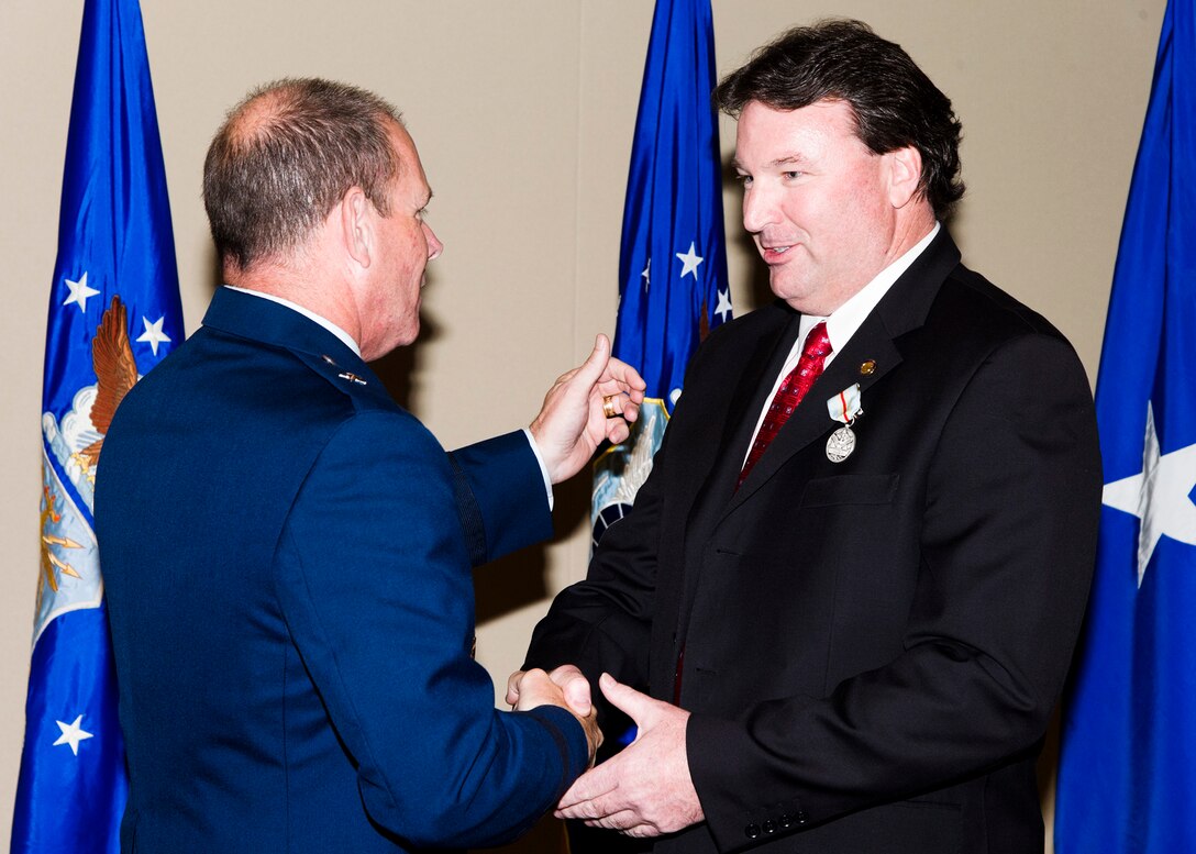 Brig. Gen. Kevin Jacobsen, OSI commander, congratulates Special Agent Bob Powers for receiving the Command Civilian Award for Valor medal. Powers rushed to the rescue of a man who had accidently caught himself on fire in a public restroom. Thanks to his actions, the man survived the day. (U.S. Air Force photo by Mr. Mike Hastings)