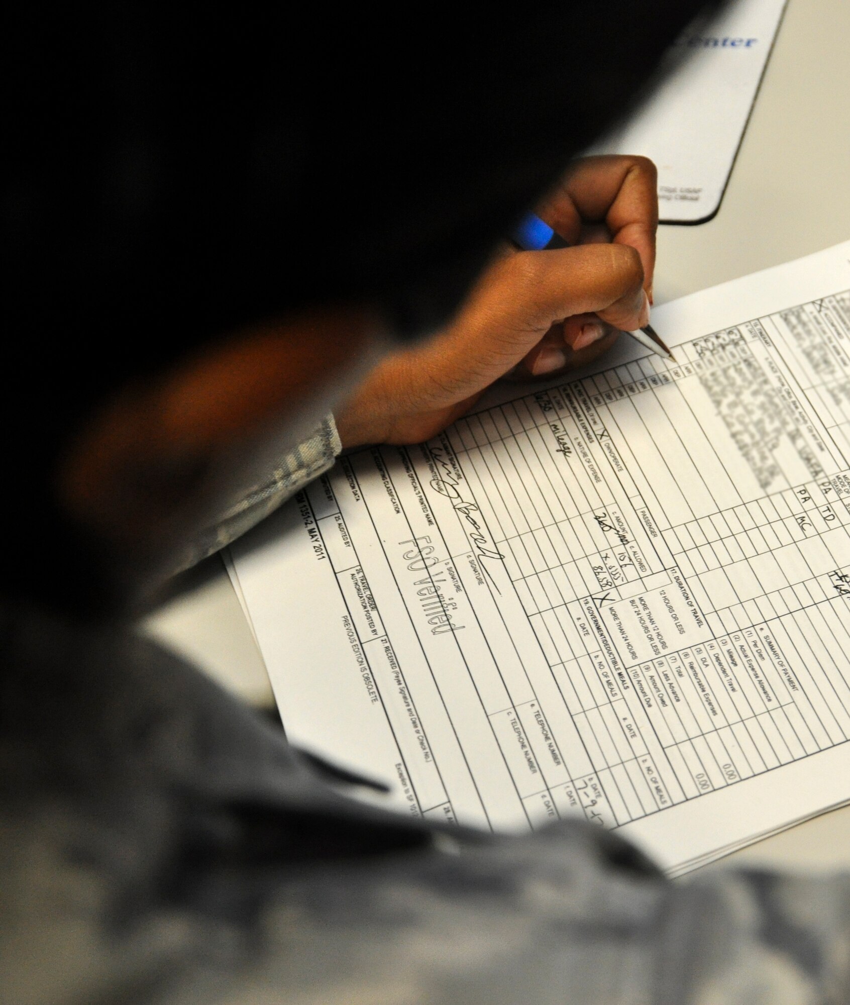 BUCKLEY AIR FORCE BASE – Senior Airman Natasha Sundar, 460th Comptroller Squadron travel team technician, reviews a travel voucher for those displaced by the Colorado wildfires.  Sundar worked with her finance team for two days at the Air Force Academy processing travel vouchers and answering questions from evacuees.  (U.S. Air Force graphic by Staff Sgt. Nicholas Rau) 