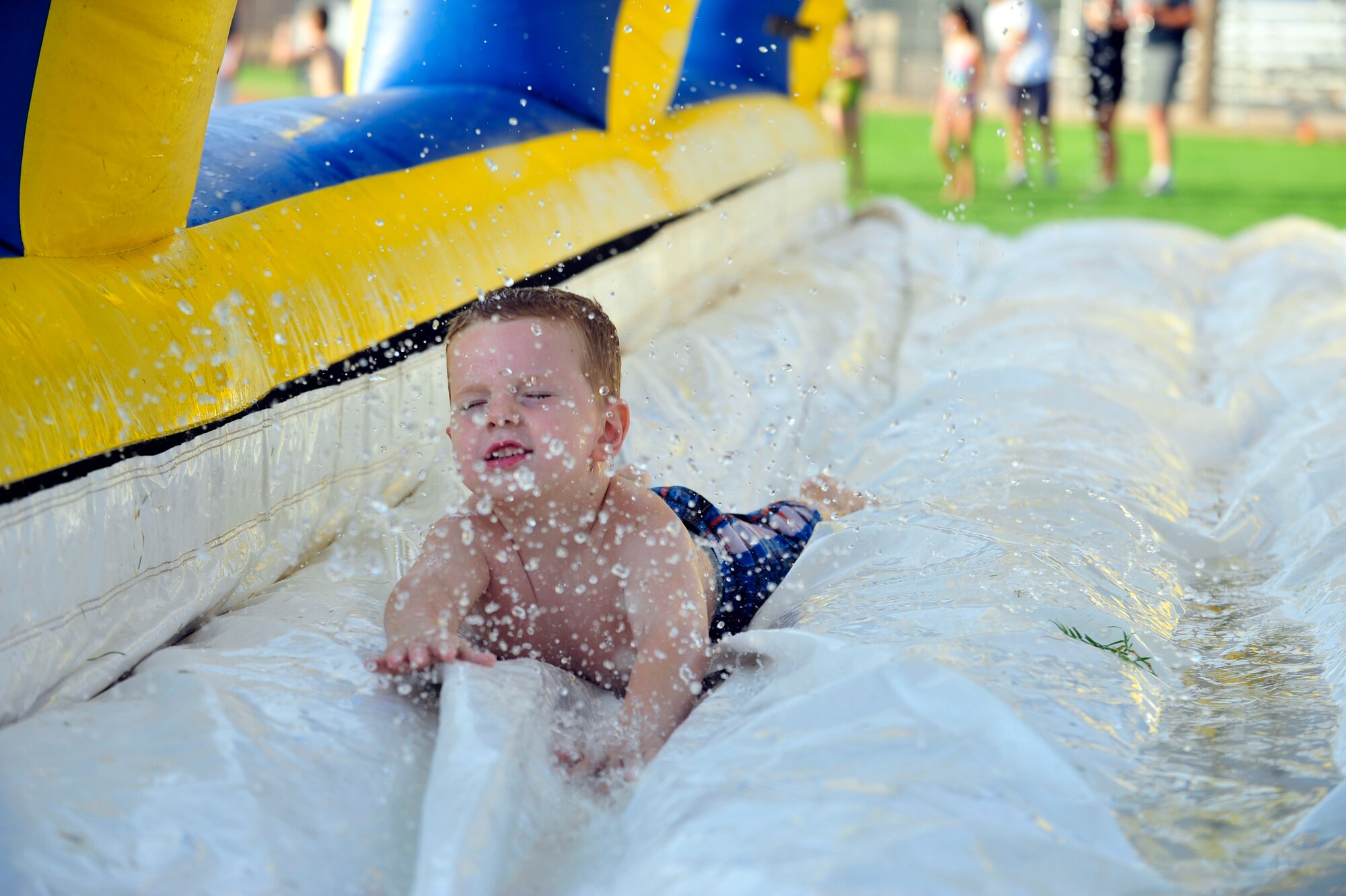 Ivan Hochhalter, 4, jumps into an inflatable splash house to cool off at Freedom Fest at Luke. Children were treated to face painting, music and a performance by the Luke Experience Theater Group.  (U.S. Air Force photo by Staff Sgt. Jason Colbert)
