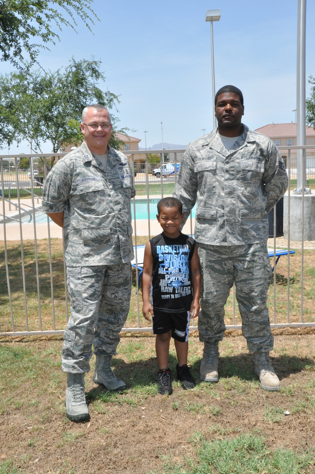 Capt. Andrew Hoeffler, 56th Medical Group family nurse practitioner, Ashawnis Guidry, 5, and Staff Sgt. Christopher Guidry, 56th Civil Engineer Squadron pavement and construction equipment operator, pose for a photo near the Balfour Beatty community pool Tuesday at Luke Air Force Base. Guidry said he is forever indebted to Hoeffler for saving Ashawnis’ life on June 23 when he successfully resuscitated him after Ashawnis nearly drowned. Phoenix Mayor Greg Stanton also recognized Hoeffler July 2 at a press conference at City Hall. (U.S. Air Force photo by Senior Airman Melanie Holochwost)	