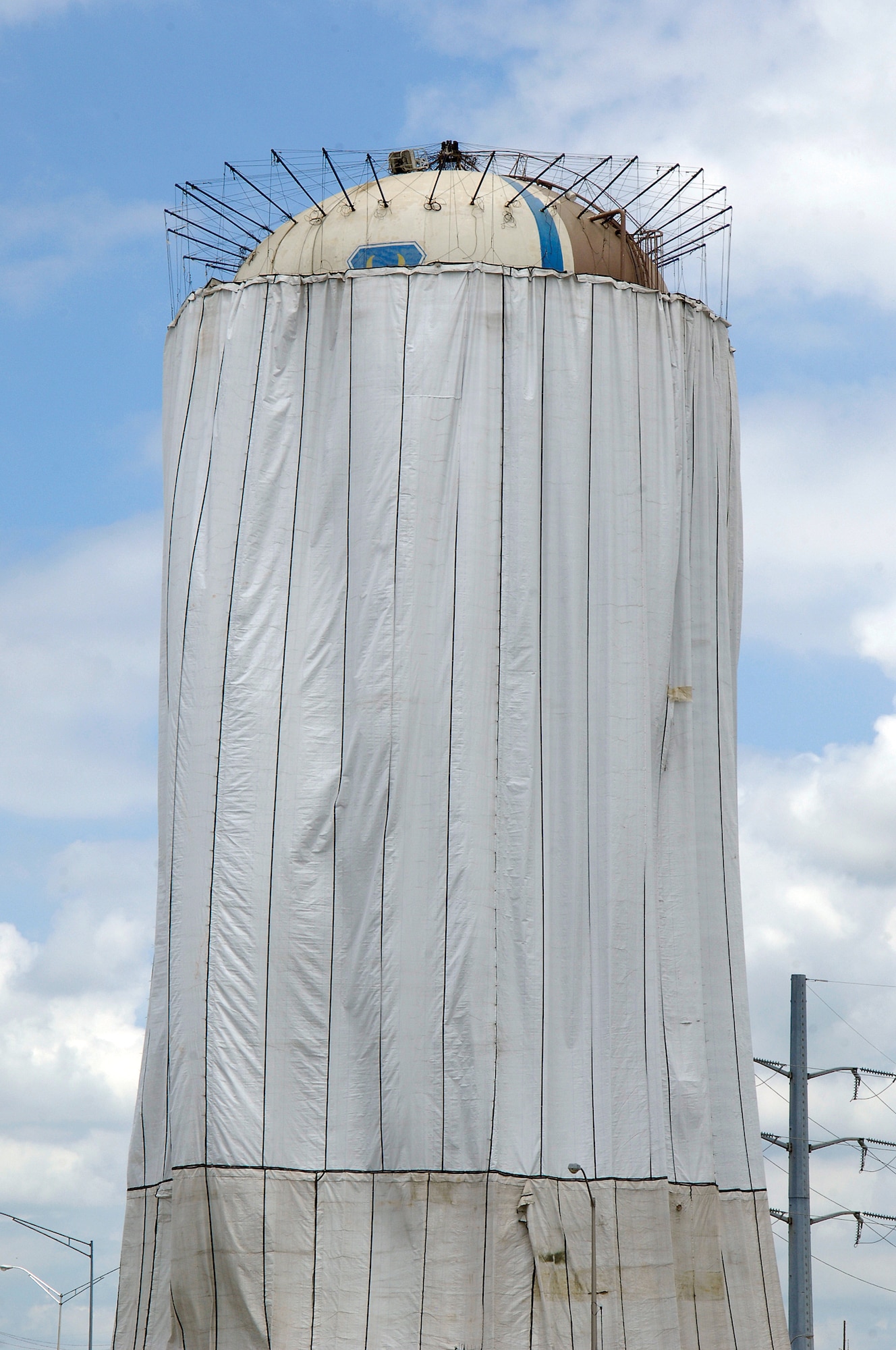 Tinker water towers that shadow I-40 near S.E. 29th street are being repainted.  The draping keeps the spraying paint on the tower and off passing cars and close buildings and protects the tower’s finish during painting.  (Air Force photo by Margo Wright)