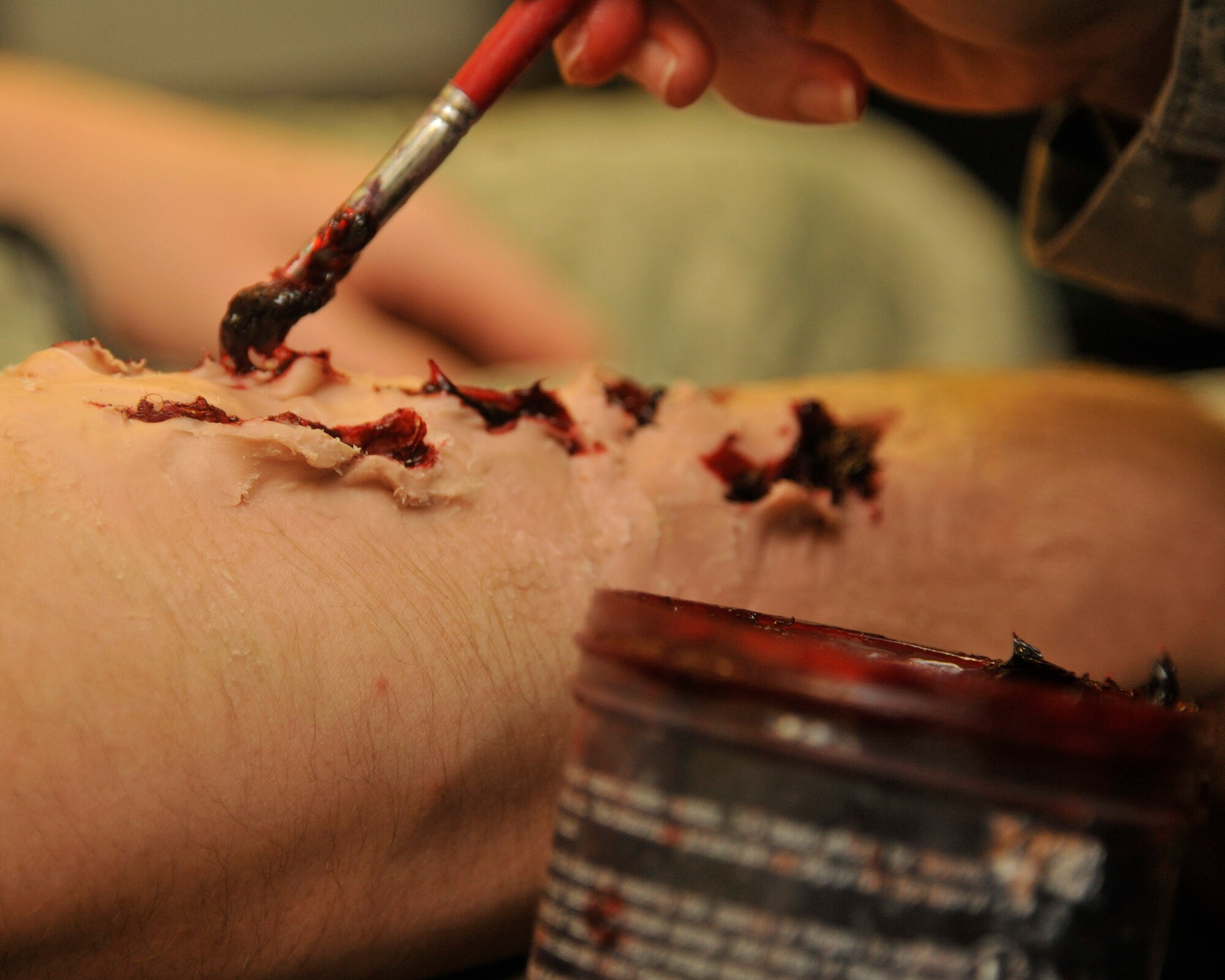 Master Sgt. Heather Bennett, 8th Medical Support Squadron, applies moulage on Airman 1st Class Nathanial Walker, 8th Maintenance Squadron, during the Beverley Midnight 12-03 exercise at Kunsan Air Base, Republic of Korea, July 11, 2012. Bennett provides realistic wounds for self-aid buddy care that would be seen in real wartime conditions. (U.S. Air Force photo/ Senior Airman Marcus Morris)