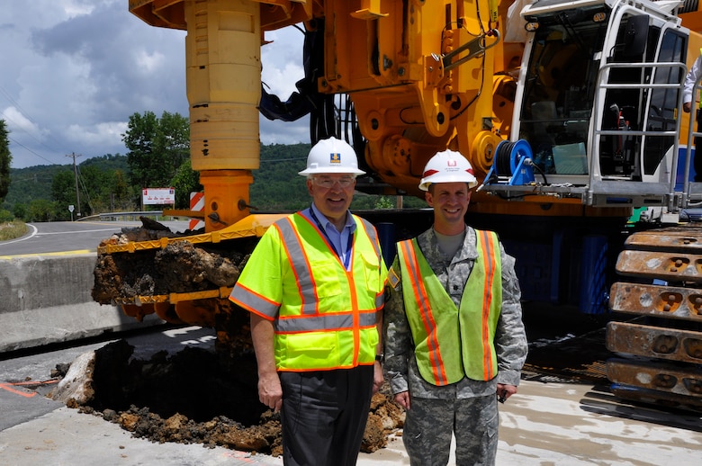 LANCASTER, Tenn. — Lt. Col. James A. DeLapp, U.S. Army Corps of Engineers Nashville District commander (right), and Professor Thomas Bauer, chief executive officer for the Bauer Group, pose in front of a drill rig July 11, 2012 that made the first excavation in the earthen portion of Center Hill Dam to install a concrete barrier wall. The $106 million project is scheduled for completion in late 2015. 