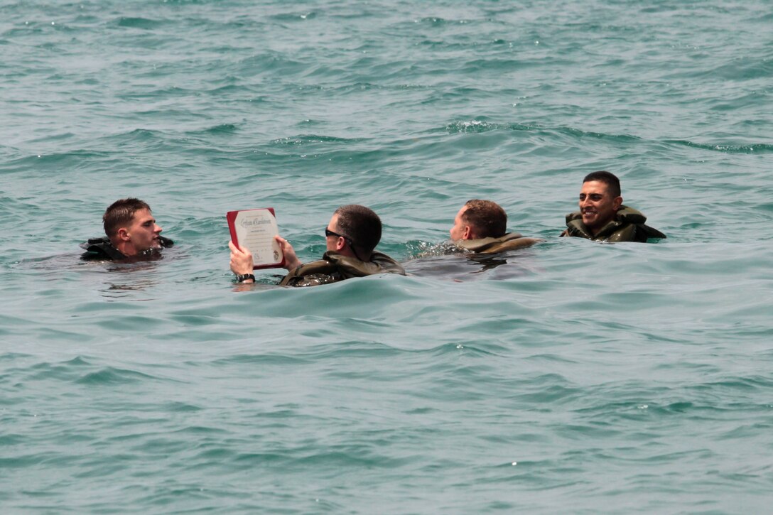 WHITE BEACH, Okinawa, Japan – Sgt. Miguel A. Gamboa (far right), a native of Friona, Texas and Sgt. Jake R. Roby (far left), a native of Grantspass, Oregon, both squad leaders from Battalion Landing Team 2nd Battalion, 1st Marine regiment, 31st Marine Expeditionary Unit, re-enlist during a company size boat raid here, July 11. Re-enlistment ceremonies are held wherever the Marines prefer and sometimes include unique and memorable places. 