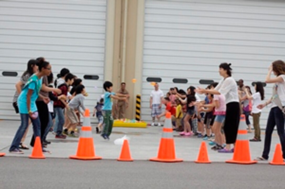 Marine Corps Air Station Iwakuni, Japan - Tsuta orphanage children and station residents throw water balloons outisde the Aircraft Rescue Fire Fighting "barn" here July 14, 2012. ARFF Marines and their families took the orphanage children to the IronWorks Gym pool and to the air field where there station is located.