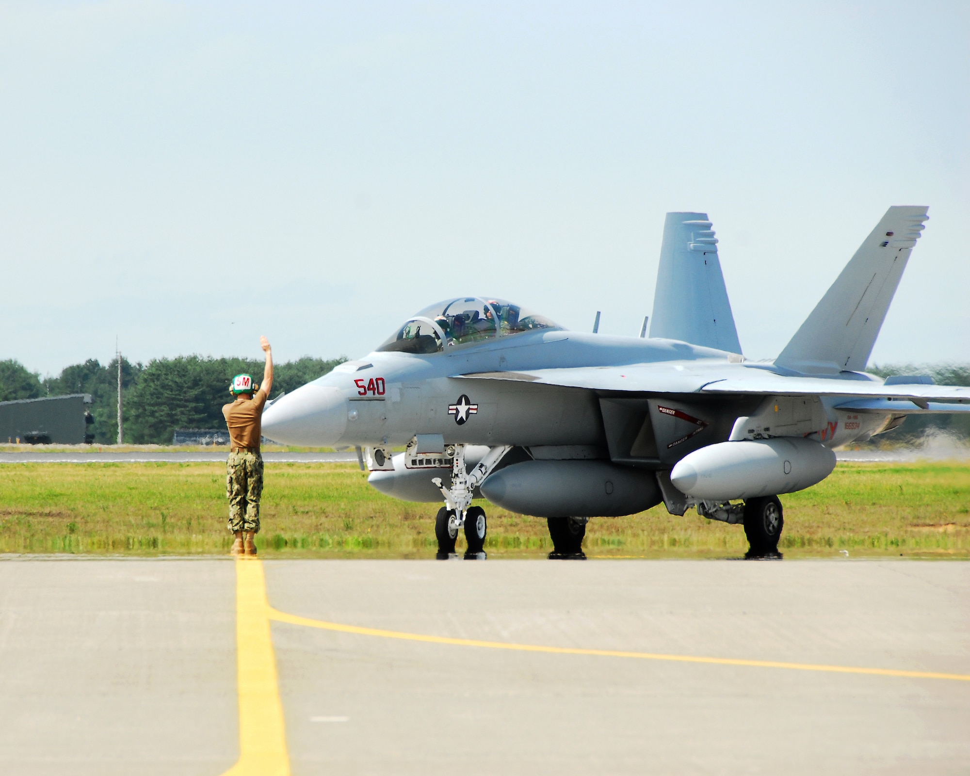 An Electronic Attack Squadron (VAQ) 132 crew member directs an EA-18G Growler as it taxis down the ramp at Naval Air Facility Misawa, Japan, July 14, 2012.  VAQ-132 is beginning a six-month deployment on board NAF Misawa and will operate largely from this northern Japan-located U.S. naval installation.  (U.S. Navy photo by Mass Communication Specialist 2nd Class Pedro A. Rodriguez/Released)