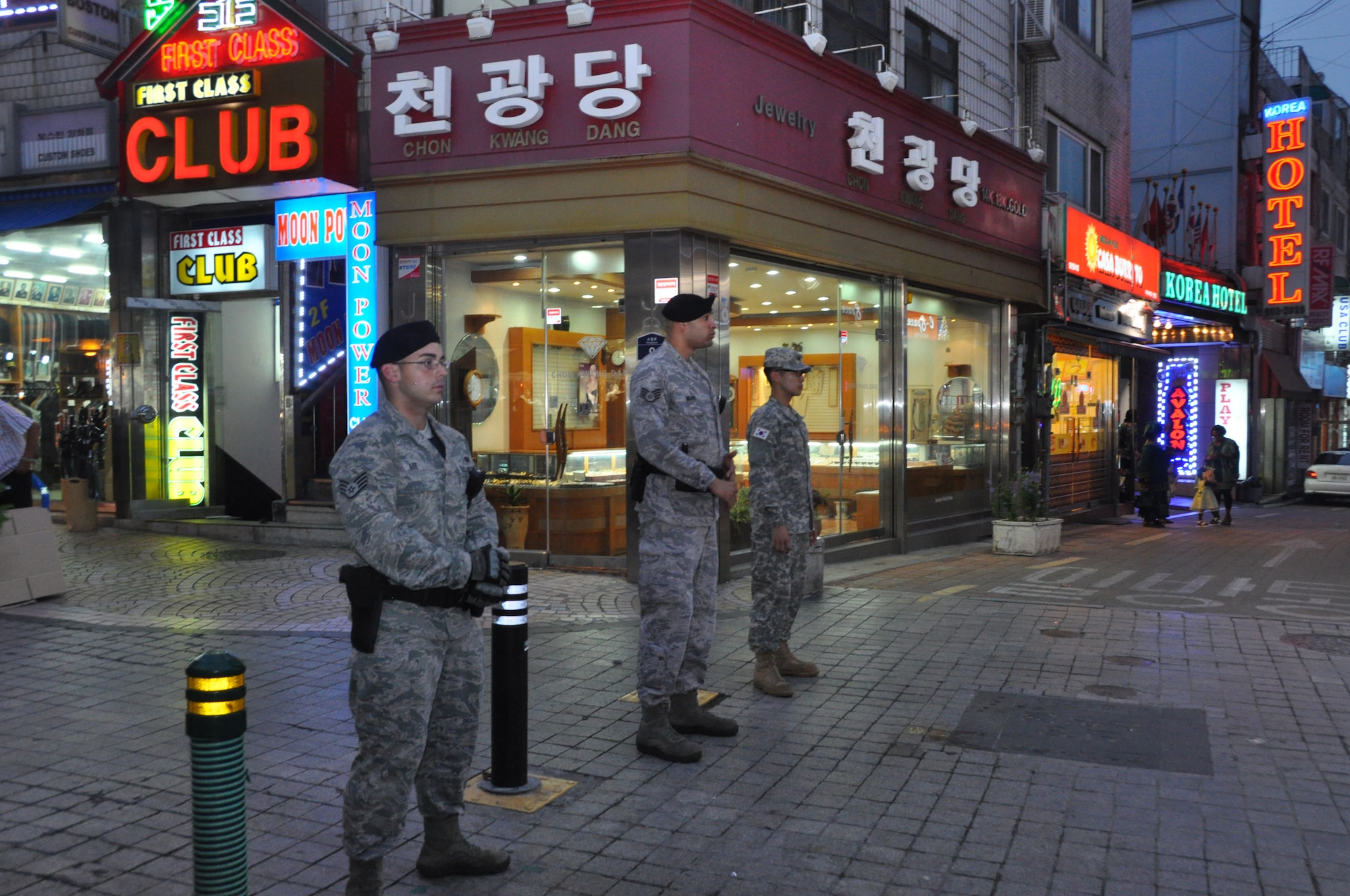 Staff Sergeants Gavin Ward and Cayman Lee, 51st Security Forces Squadron town patrolmen, survey the streets of the Songtan Entertainment District just outside of Osan Air Base alongside a Republic of Korea Army soldier, July 12, 2012.  Korean Augmentees to the U.S. Army will now accompany town patrols to act as translators between Korean locals and U.S. service members. This is the first time U.S. Airmen and KATUSAs have patrolled together. (U.S. Air Force photo/Senior Airman Michael Battles)