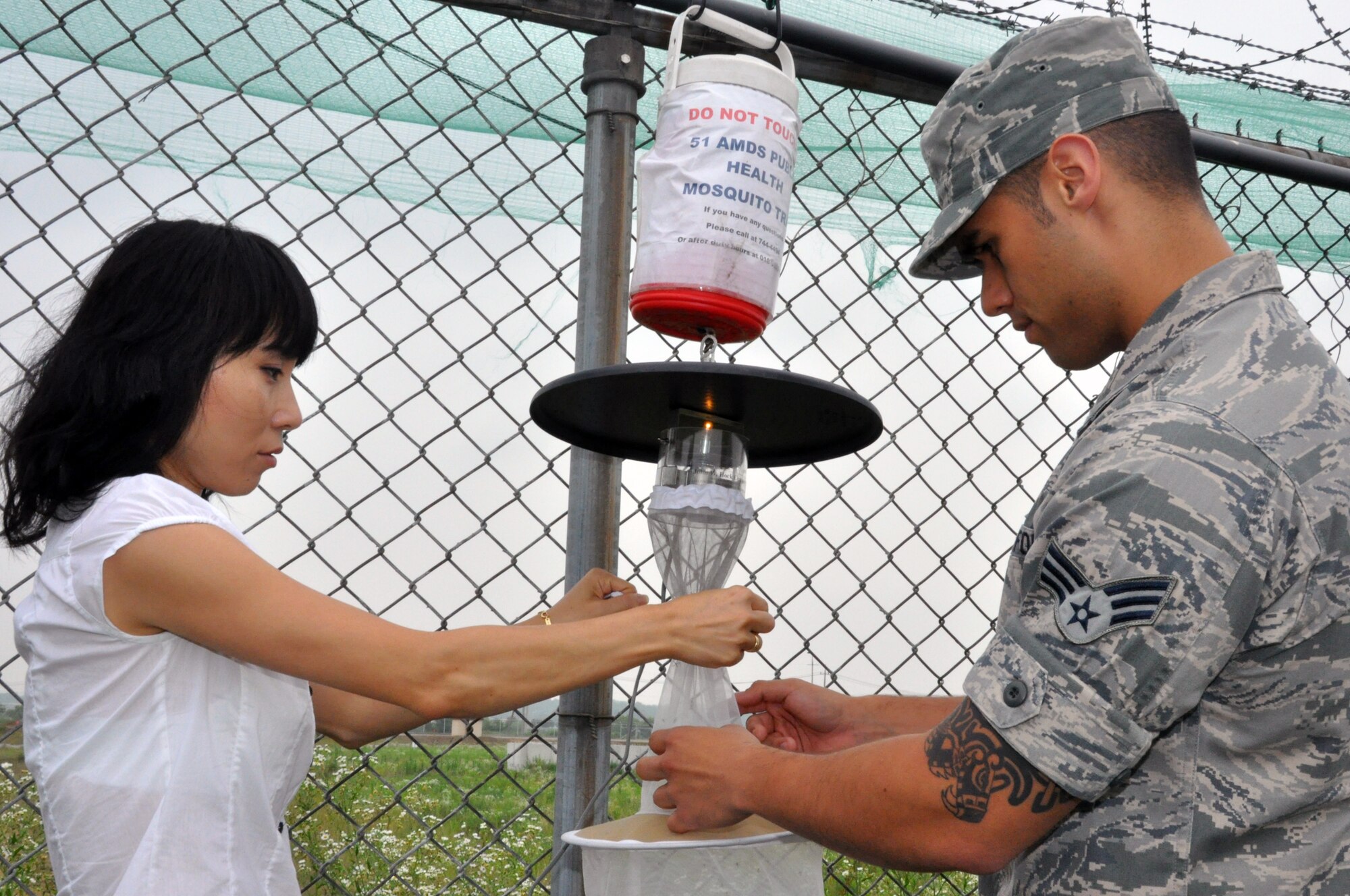 Hyon Chu So and Senior Airman Rene Martinez, both 51st Aerospace Medicine Squadron Public Health technicians, empty a mosquito trap at Osan Air Base, Republic of Korea, July 12, 2012. The Public Health Office monitors the amount of mosquitoes on base from May until October every year. This year more than 2,000 mosquitoes have been caught, sorted and analyzed for disease.  (U.S. Air Force photo/Senior Airman Michael Battles)