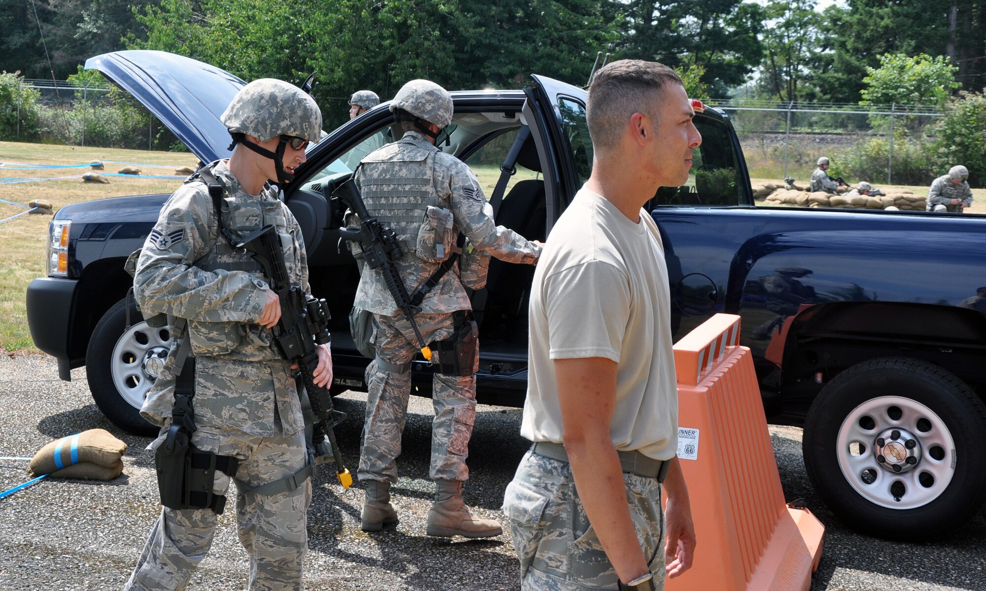 MCCHORD FIELD, Wash. - (Left) Senior Airman Barrett Horn, 446th Security Forces Squadron here, stands guard over a mock suspect (right) played by Tech. Sgt. David Buchanan, 446th SFS, while training July 14.  Pictured center is Staff Sgt. Casey Drab, 446th SFS, who is conducting an initial vehicle search for explosives. Members of the 446th SFS are preparing for their unit’s first ever participation in an Operational Readiness Inspection at Volk Field, Wis., in October. (U.S. Air Force photo by Tech. Sgt. Elizabeth Moody)