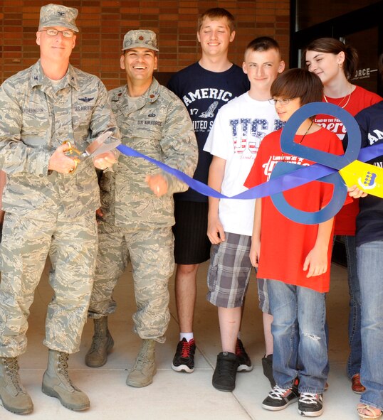 Col. Mark Weatherington, 28th Bomb Wing comander, is joined by Maj. David Burnett, 28th Force Support Squadron commander, and several base teenagers as he cuts the ribbon marking the opening of the 28th FSS Teen Center at its new location in Bldg. 7712, July 6, 2012. The center offers young adults on base who are currently in high school the opportunity to interact with other teens, participate in educational programs and enjoy recreational activities. (U.S. Air Force photo by Airman Ashley J. Cass/Released)