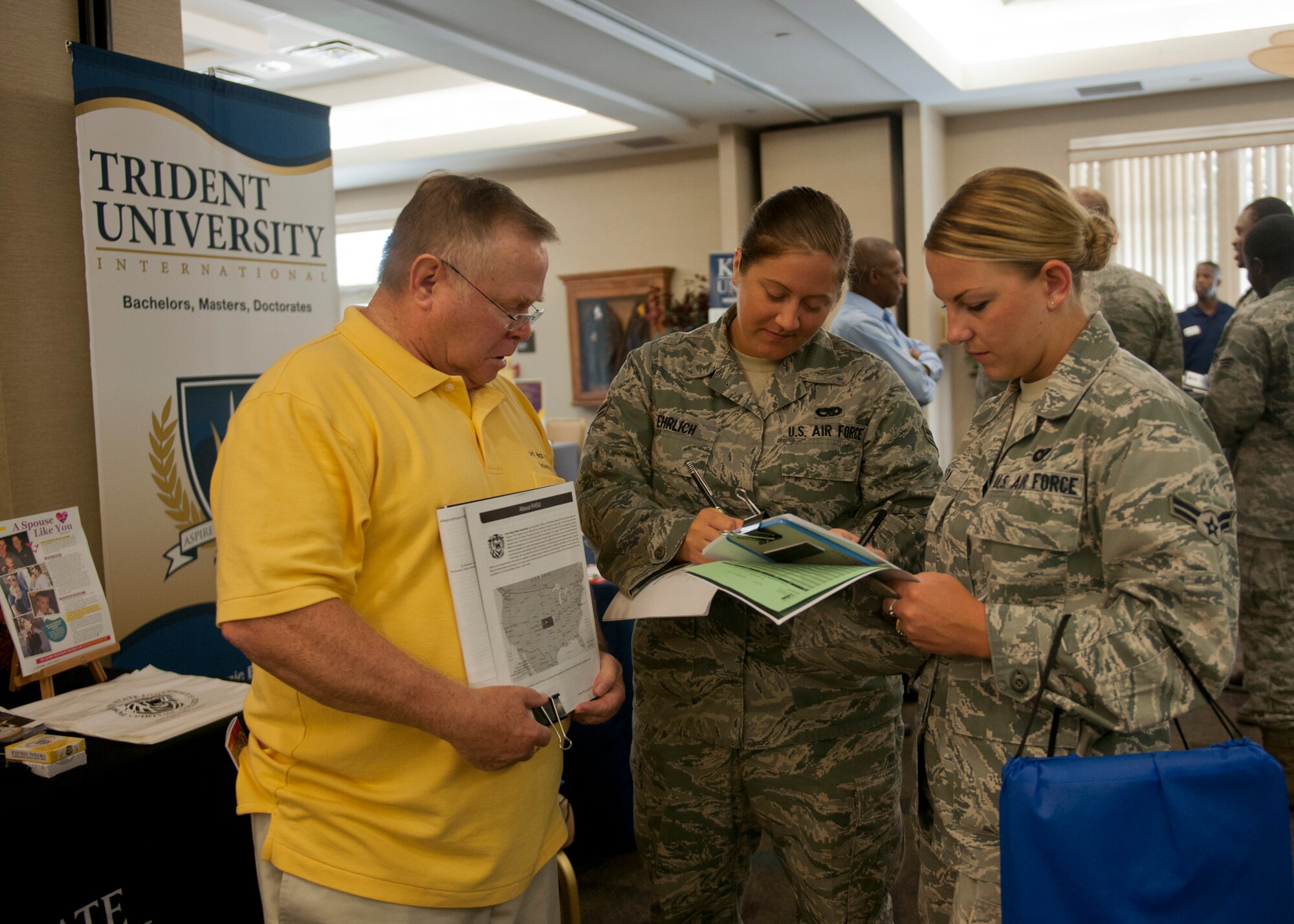 Skip Habina, local representative for Fort Hays State University, speaks with U.S. Air Force Airmen 1st Class Holly Ehrlich, 23d Maintenance Operations Squadron scheduler, and Lindy Pata, 23d Wing Public Affairs broadcaster, about FHSU during an education fair July 12, 2012, at Moody Air Force Base, Ga. More than 20 schools set up displays educating Airmen and other attendees about furthering their education. (U.S. Air Force photo by Senior Airman Eileen Meier/Released)