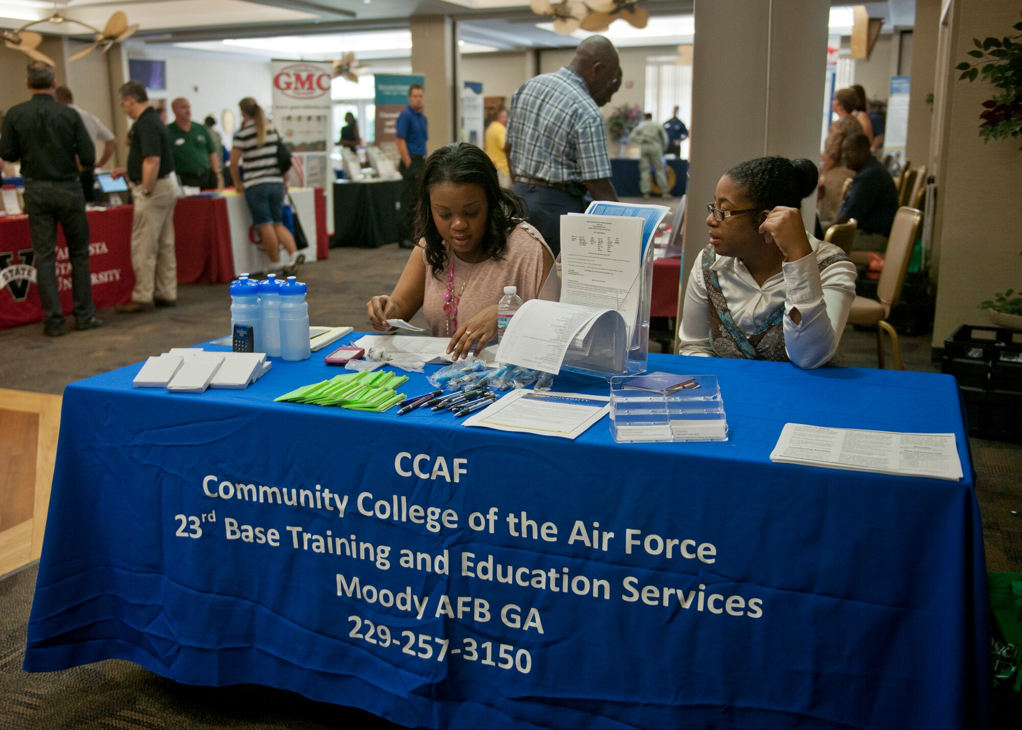 Shalarie Montgomery, education counselor, and Katrice Colvin, education center technician, both from the 23d Force Support Squadron, encourage Airmen to pursue their degree with the Community College of the Air Force during an education fair July 12, 2012, at Moody Air Force Base, Ga. Several other military-friendly schools set up displays and handed out unique souvenirs such as playing cards, calculators and stress balls. (U.S. Air Force photo by Senior Airman Eileen Meier/Released)