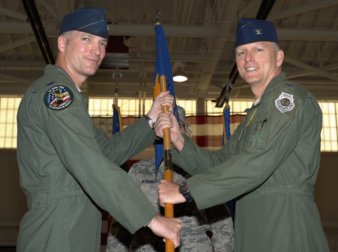 U.S. Air Force Col. Kevin Robbins, left, 1st Fighter Wing commander, presents the 1st Operations Group guidon to Col. Edward Corcoran, the new 1st OG commander, during a change-of-command ceremony at Langley Air Force Base, Va., July 13, 2012. Corcoran has flown more than 2,800 hours, including 185 combat hours in F-15 Eagles. (U.S. Air Force photo by Tech. Sgt. Barry Loo/Released)
