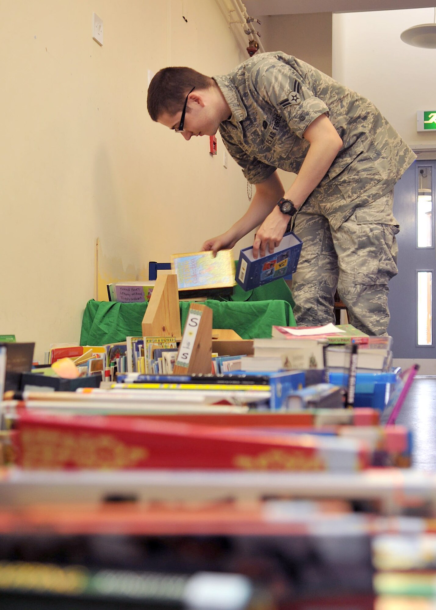 BECK ROW, England - Airman 1st Class Weston Williams, 100th Communications Squadron, sorts through stacks of books at the Beck Row Primary School July 16, 2012. Several Airmen from RAF Mildenhall assisted the local school with the set up of a new library room. (U.S. Air Force photo/Senior Airman Jerilyn Quintanilla)