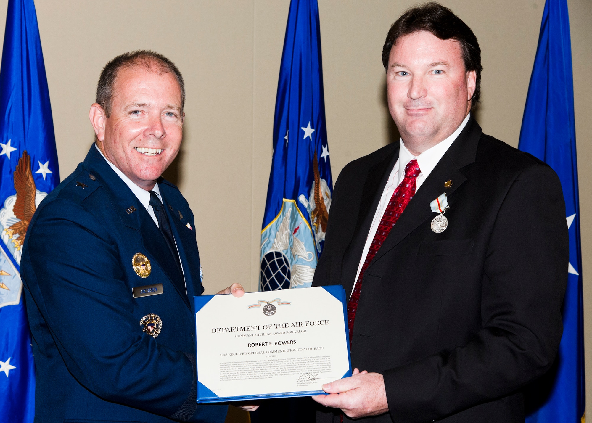 Brig. Gen. Kevin Jacobsen congratulates Special Agent Bob Powers for receiving the Command Civilian Award for Valor medal. Powers received the medal for rescuing a man who had accidently caught himself on fire in a public restroom. Thanks to his actions, the man survived. Jacobsen is the Air Force Office of Special Investigations commander. (U.S. Air Force photo/Mike Hastings) 
