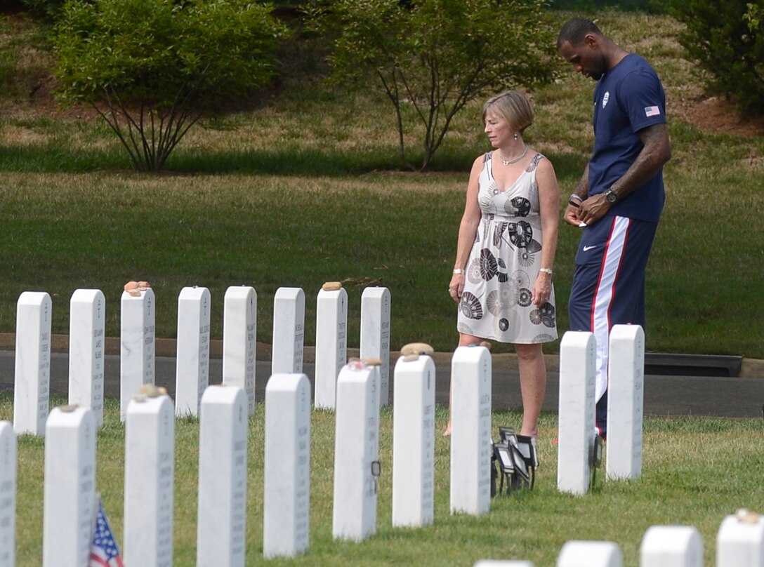 Deanie Dempsey, wife of Army Gen. Martin E. Dempsey, chairman of the Joint Chiefs of Staff, waits while LeBron James writes a note for a fallen soldier buried in Section 60 of Arlington National Cemetery, Arlington, Va.,  July 15, 2012.   