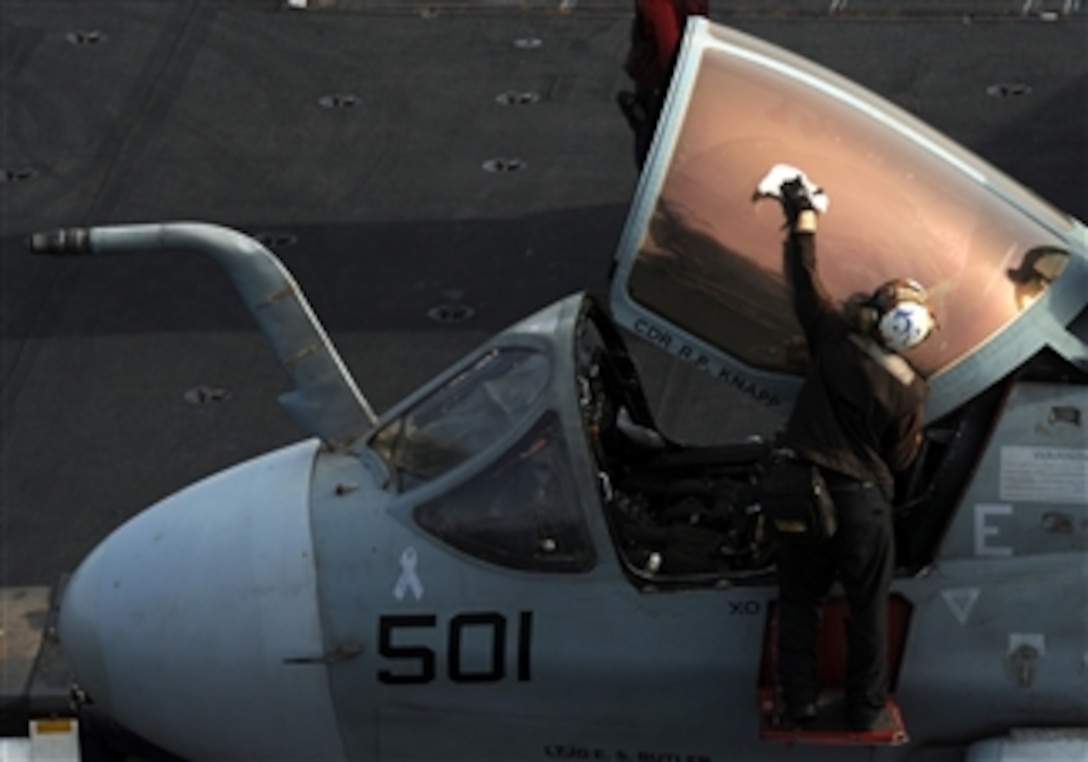 A plane captain assigned to Electronic Attack Squadron 131 wipes down the canopy of an EA-6B Prowler on the flight deck of the Nimitz-class aircraft carrier USS Abraham Lincoln as the ship operates in the Arabian Sea on July 11, 2012.  Lincoln is deployed to the U.S. 5th Fleet area of responsibility conducting maritime security operations and theater security cooperation efforts.  