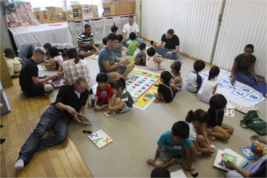 Community-relations event volunteers sit with children at the Josho Hoikuen Preschool July 17, 2012, as the volunteers teach the children the English alphabet and numbers. Approximately 32 volunteers spent the morning with the children, reading and teaching them English and playing an assortment of games such as “Duck, duck, goose” and “Head and Shoulders.”