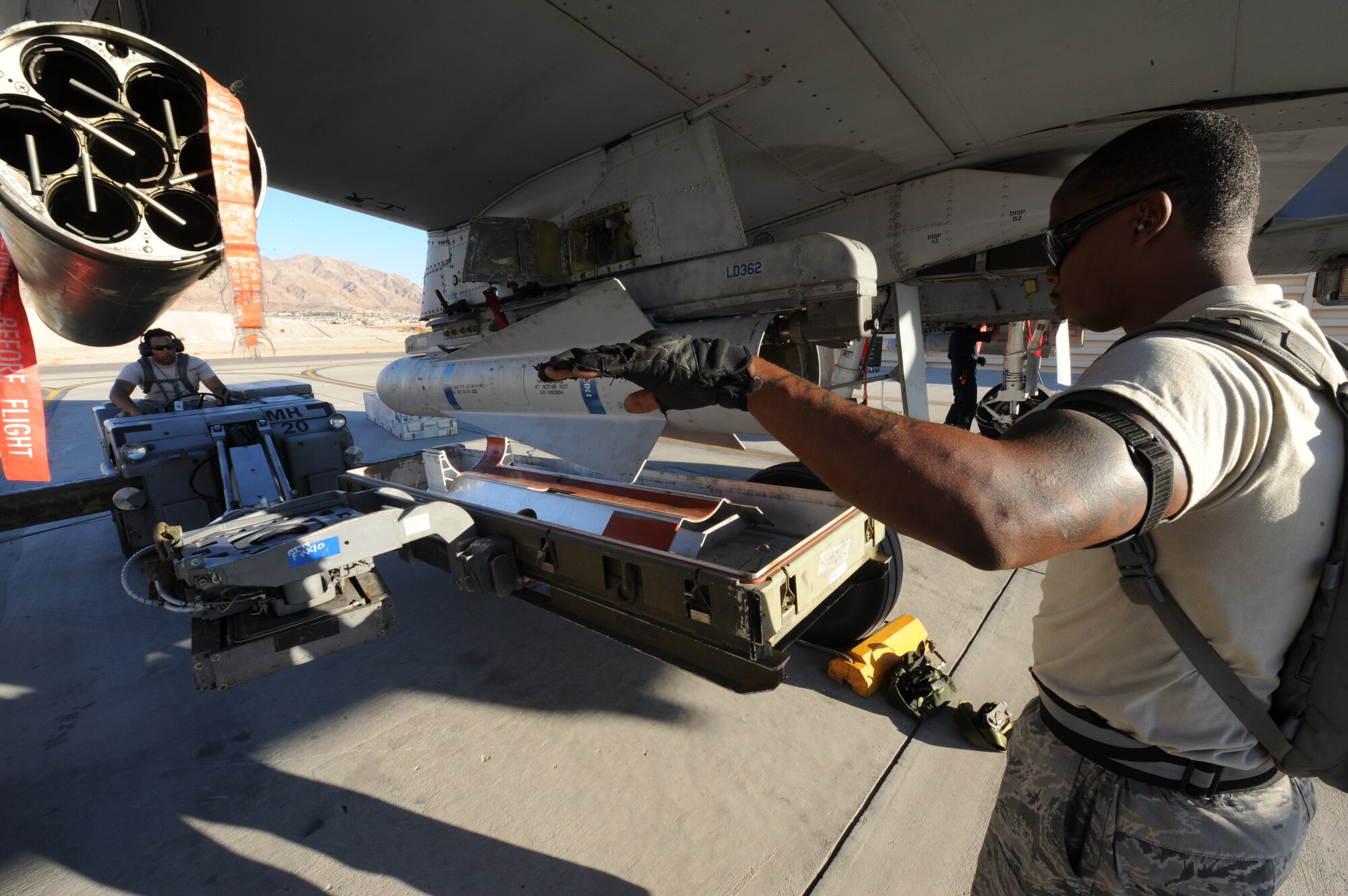 U.S. Air Force Senior Airman Michael Tomaski, 23d Aircraft Maintenance Squadron, 74th Aircraft Maintenance Unit, positions an MHU-83 bomb lift truck into position for unloading ordnance while Staff Sgt. Robert Smith gives direction.  The two Airmen are part of a three-man crew loading ordnance onto an A-10C Thunderbolt II, July 16, 2012, at Nellis Air Force Base, Nev., during Red Flag 12-4 exercise. Once the ordnance is loaded, the aircraft is ready for its next mission.  The teams work together to load the weapons as quickly, but as safely as possible. (U.S. Air Force photo by Master Sgt. Sonny Cohrs/Released)