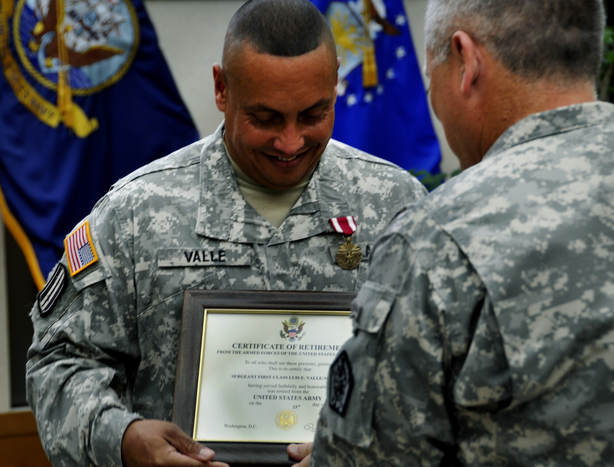 Army Sergeant 1st Class Luis Valle, Army Liaison noncomissioned officer in charge, looks down at the Certificate of Retirement presented to him by Army Lt. Col. Mark Laney, Joint Personnel Effect Depot Commander, on behalf of the President during Valle’s retirement ceremony at the Charles C. Carson Center for Mortuary Affairs, Dover Air Force Base, Del., July 12, 2012. Valle retired after 29 years of service. He has worked at the Dover Port Mortuary for more than 5 years taking care of fallen soldiers and their families.  (U.S. Air Force photo/Staff Sgt. Caitlin Jones) 