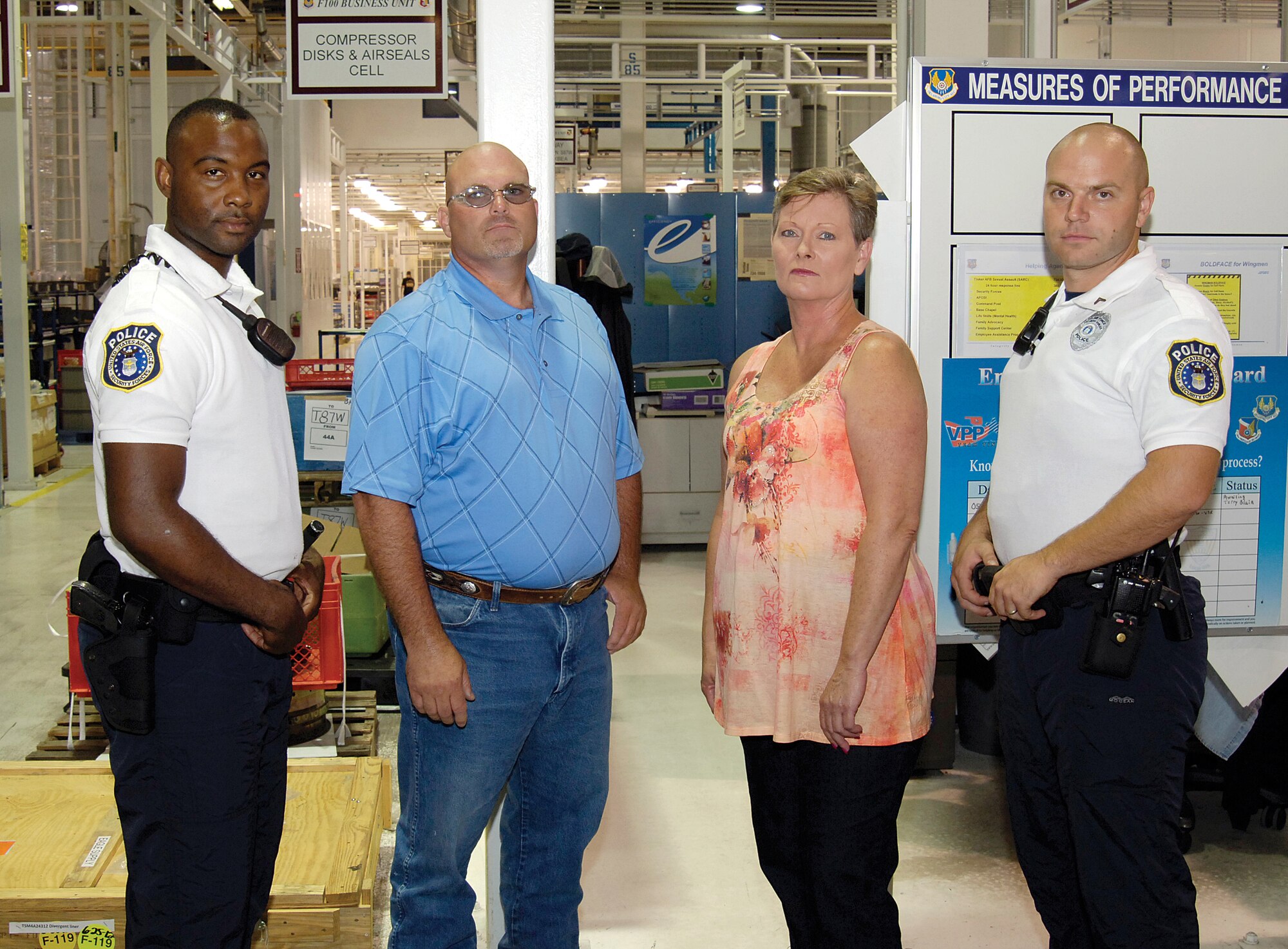 Tech. Sgt. Keith Hagins, 72nd Security Forces Squadron; Rodney Walker and Cheryl Sweeney, both of the 544th Propulsion Maintenance Squadron; and officer Aaron Whitehead, 72nd SFS, from left, acted instinctively, demonstrating the highest example of being Wingmen when they saved the life of a 544th PMXS co-worker found June 18 crumpled on the floor of his Bldg. 3001 work area, shown behind them in the F100 Compressor Cell. (Air Force photo by Margo Wright)