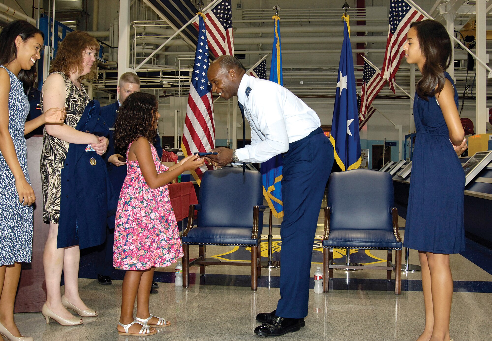 During his July 9 promotion ceremony at Hollywood and Vine in Bldg. 3001, Brig. Gen. Cedric George’s daughter Sydney hands her father his hat bearing his new rank.  Participating in the ceremony were, from left, daughter Morgan, wife Liz, and daughter Hannah. Commander of Tinker’s 76th Maintenance Wing until the July 10th deactivation here, the general will assume command of the newly-restructured Warner-Robins Air Logistics Complex in Georgia. (Air Force photo by Margo Wright)