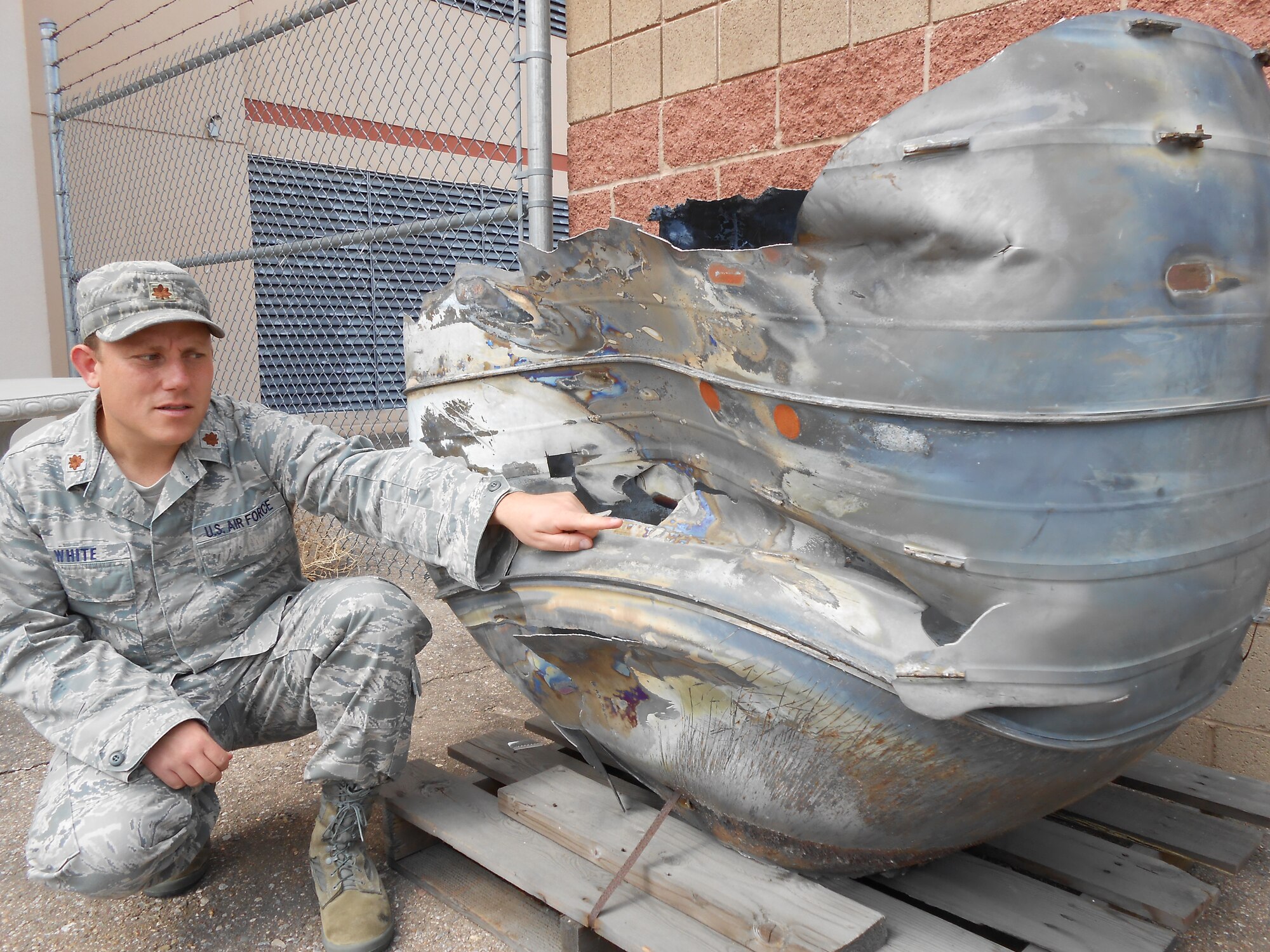 Maj. Justin White, deputy chief, Space Safety Division, Air Force Safety Center, takes a look at reentered space debris from a Delta II rocket motor recovered in Thailand in 2005. The division is responsible for enabling full-spectrum combat space capabilities via mishap prevention. The potential for a space mishap increases as more debris is added to the 22,000-plus pieces that are tracked.  (U.S. Air Force photo)
