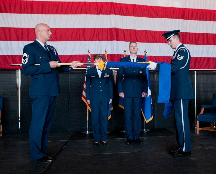 HANSCOM AIR FORCE BASE, Mass. - Chief Master Sgt. Baird Stiefel (left), Hanscom AFB senior enlisted advisor, furls the Electronic Systems Center flag with assistance
from Patriot Honor Guard member Tech. Sgt. Richard Leger during the ESC
Transition Ceremony July 16 at the Aero Club Hangar, when ESC transitioned
to become a part of the Air Force Life Cycle Management Center. Gen. Janet
Wolfenbarger, Air Force Materiel Command commander, who presided over the
ceremony, and Col. Mark Spillman, ESC commander at the time, stand at
attention during the presentation.  (U.S. Air Force photo by Mark Wyatt)