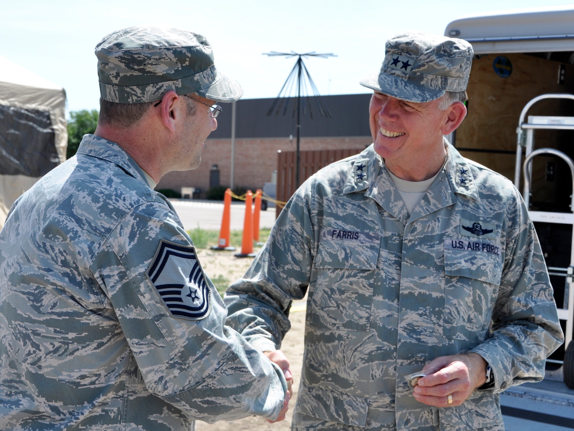 Air Force Reserve Senior Master Sgt. Terry Brassard presents the 302nd Airlift Wing Family Day coin to Maj. Gen. Wallace W. “Wade” Farris, Jr., as the general toured the 302nd Airlift Wing July 15 at Peterson Air Force Base, Colo. Farris, who commands the 22nd Air Force, the parent organization to the 302nd Airlift Wing, visited the wing to see its mission firsthand as well as gain a better understanding of its involvement with the recent Modular Airborne Fire Fighting System, or "MAFFS" activation to battle the nearby Waldo Canyon Fire. The general also coined a number of Air Force Reservists who had gone above and beyond in their respective 302nd AW positions. Farris visited the wing July 14-17. Brassard is the 302nd Force Support Squadron superintendent and Family Day chairman. (U.S. Air Force photo/Staff Sgt. Stephen J. Collier)