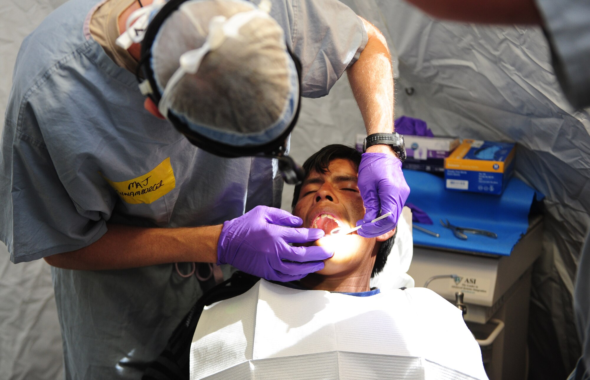 U.S. Air Force Maj. Nathon Schwamburger, left, extracts a tooth from a Peruvian patient at a health response team Expeditionary Medical Support mobile field hospital in Huancavelica, Peru, July 2, 2012, during New Horizons 2012. Schwamburger is deployed from Langley Air Force Base, Va., for training, and to provide humanitarian and medical services. (U.S. Air Force photo by Staff Sgt. Michael C. Zimmerman/Released)